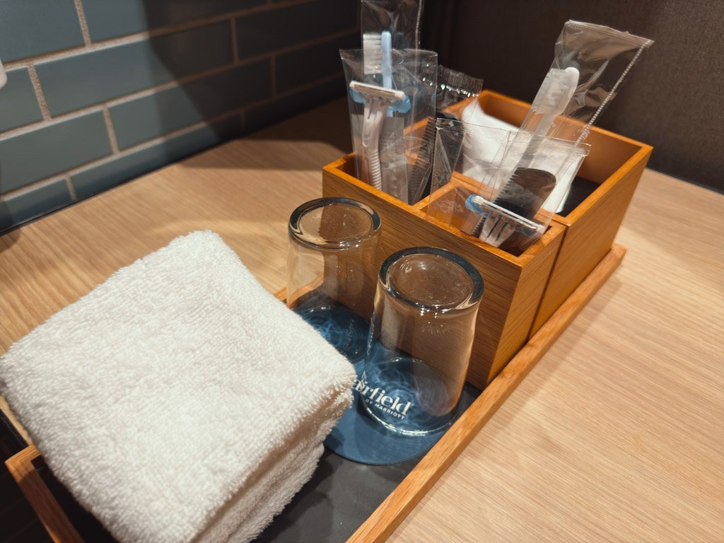 客室内の洗面スペースに置かれたアメニティセット。グラス、タオル、歯ブラシなどの備品が整然と並べられている。