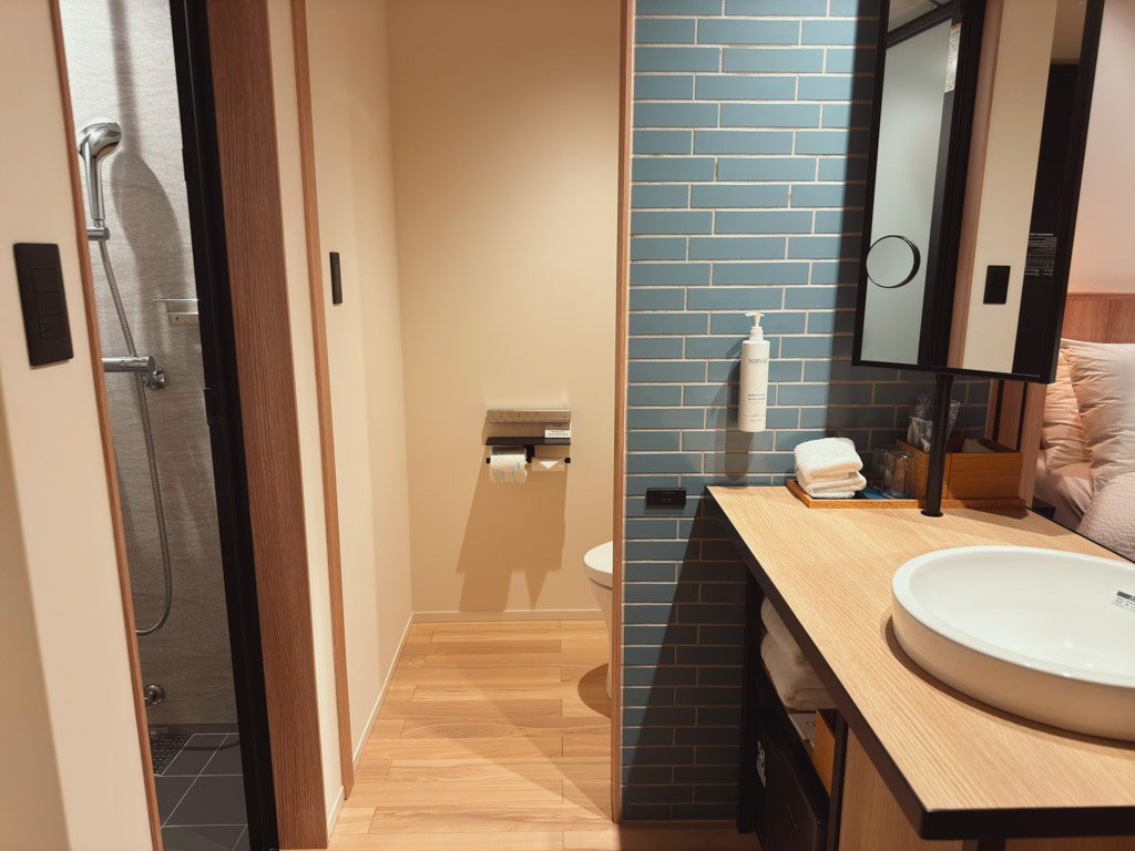 客室内のバスルームと洗面スペース。青いタイルが特徴的で、シャワールームとトイレが独立しています。