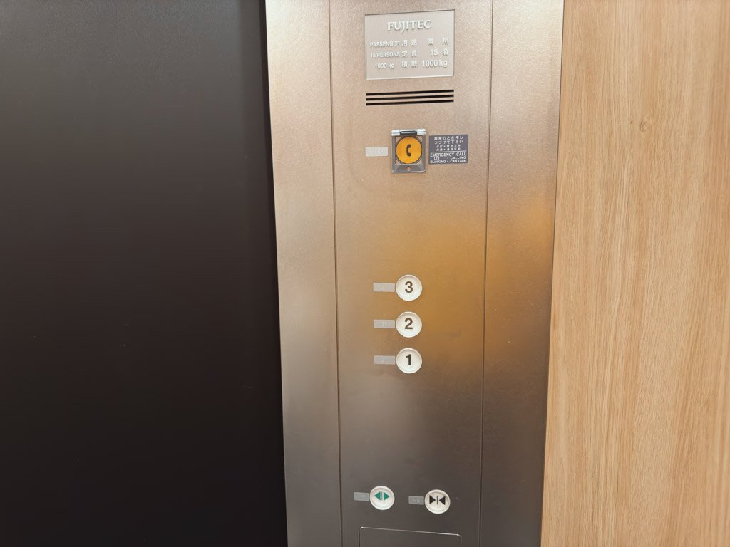 エレベーター内の操作パネル、1階から3階までのボタンが並んでいます。