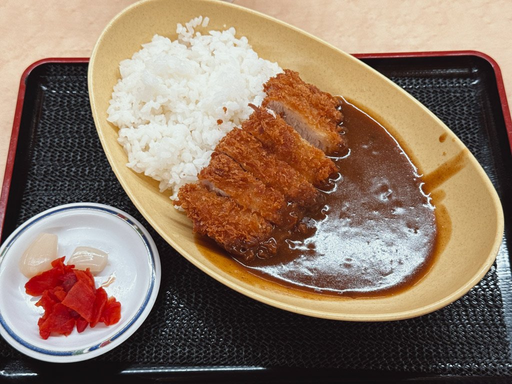 丹波大食堂で注文したカツカレー。カツがサクサクでカレーのルーがたっぷりかかっており、ご飯と福神漬けが添えられています。
