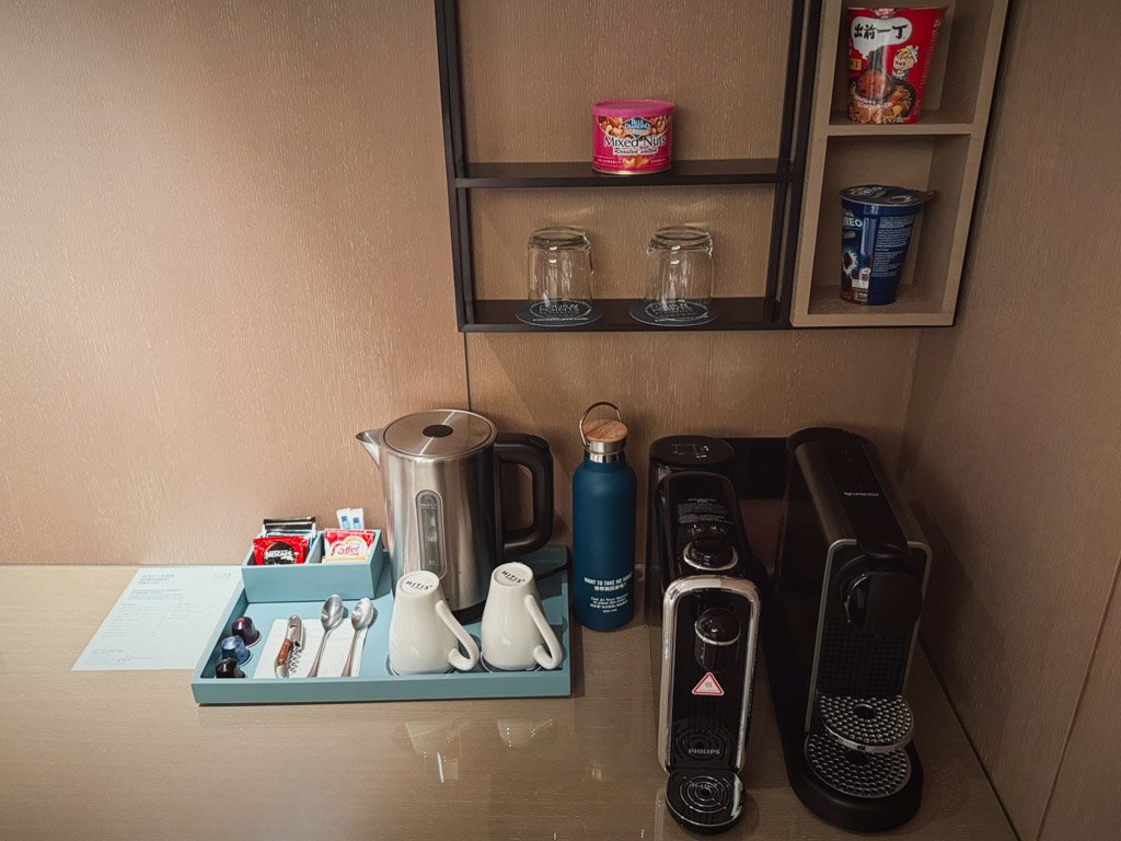  フォーポイントバイシェラトン香港、東涌の客室内にあるカウンターエリア。コーヒーメーカー、ティーセット、電気ケトルが整然と並べられている。中央には青いウォーターボトルが置かれている。 