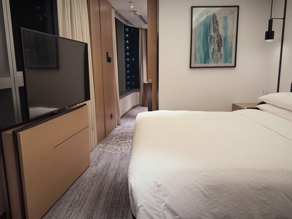  フォーポイントバイシェラトン香港、東涌の客室内、ベッドとテレビ、その奥に続く廊下とバスルーム。 