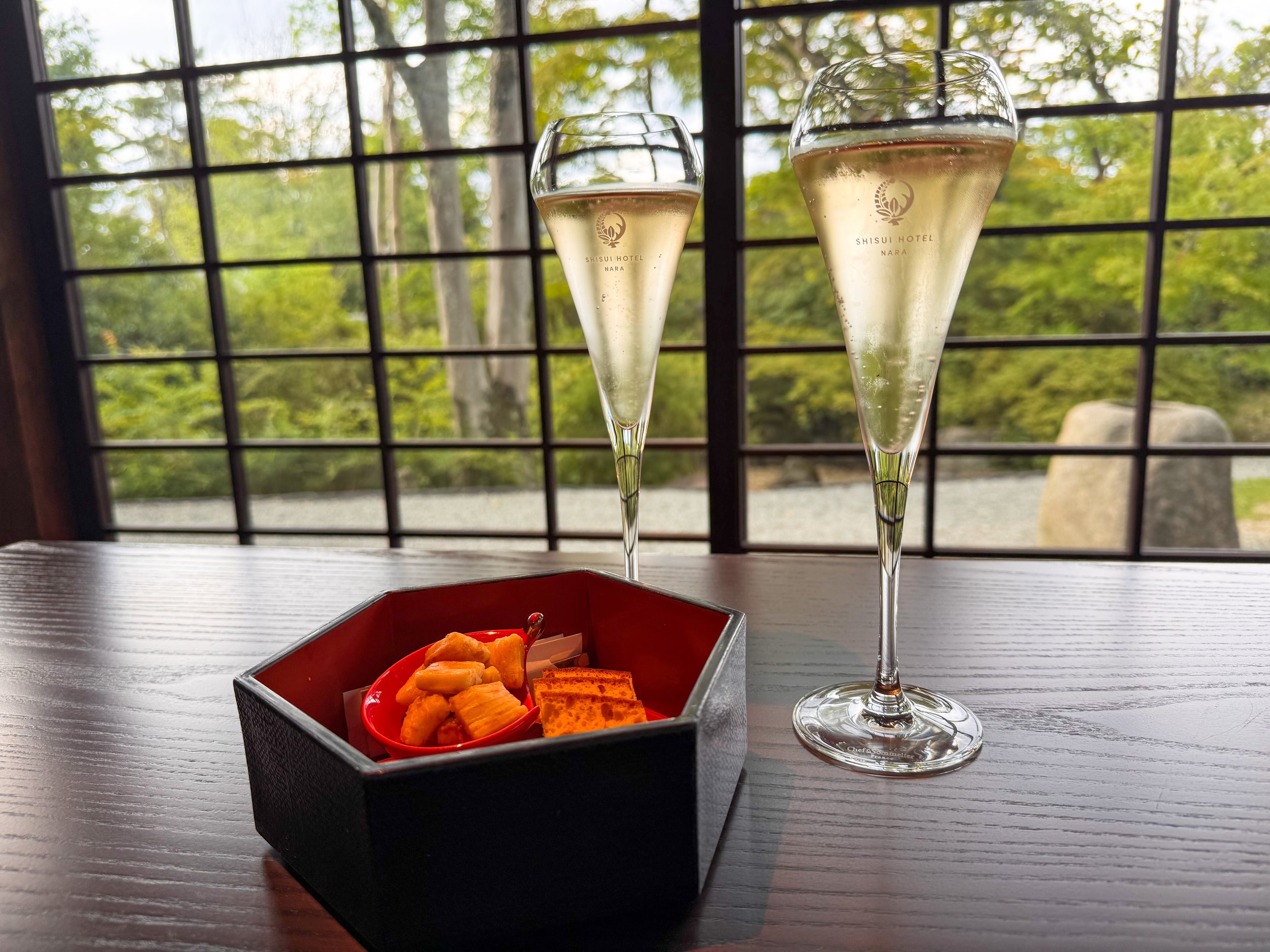  シャンパンと和菓子が並ぶ和の雰囲気が漂うテーブル、ガーデンビューが美しい  A table with champagne and Japanese sweets, set in a serene Japanese atmosphere with a beautiful garden view 