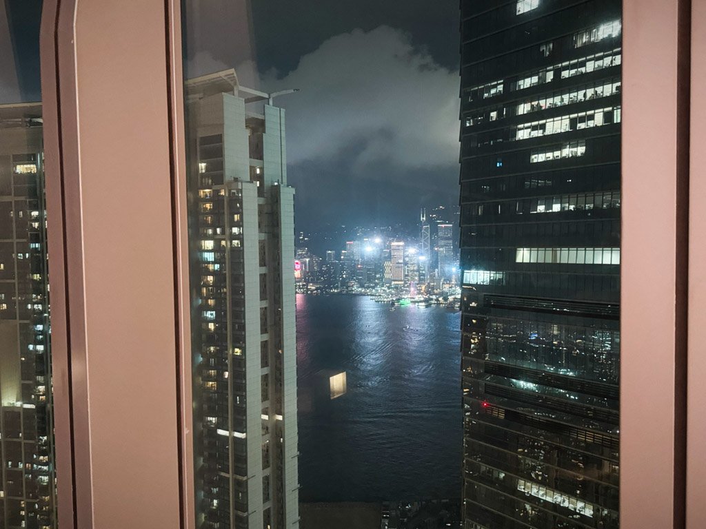  部屋の窓から見える香港の夜景。ビルの光が反射してビクトリアハーバーの美しい夜景が広がっています。 