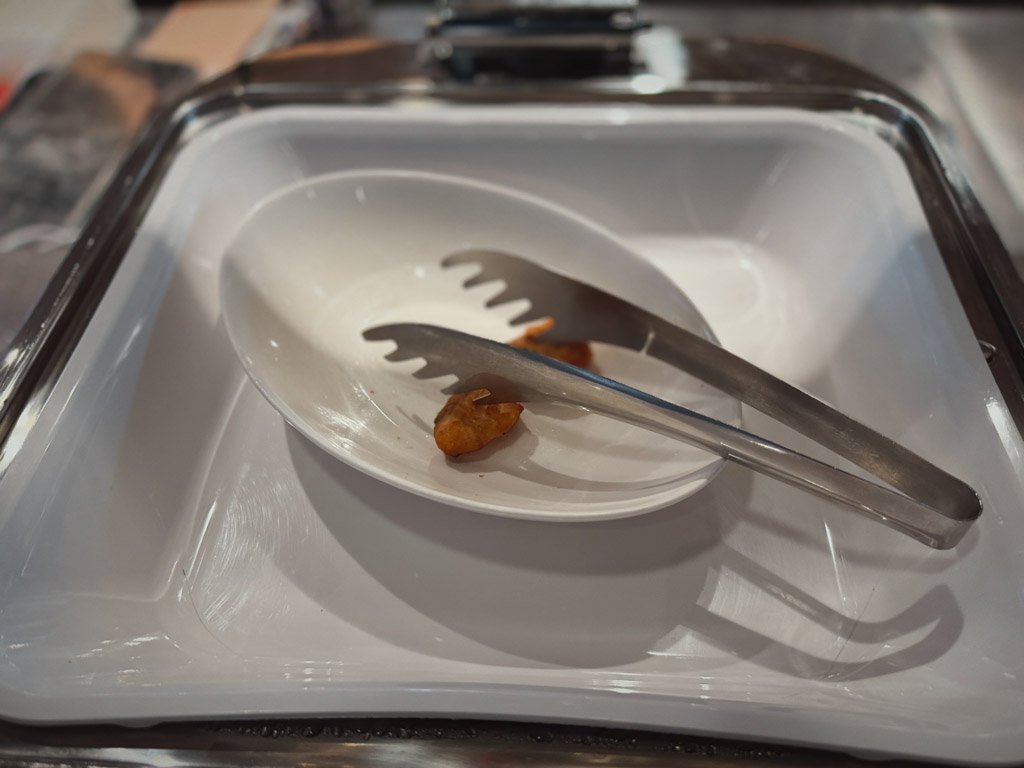 モクシー大阪本町の朝食ビュッフェエリアにて。空になりかけているトレーに残ったポテトの一部が白い皿に盛られ、トングが横に置かれています。