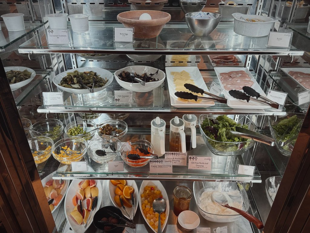 モクシー大阪本町の朝食ビュッフェの冷蔵ケース内。野菜、チーズ、ハム、ドレッシング、フルーツなどが整理されて陳列されており、訪れるゲストが自由に選べる形式になっている。
