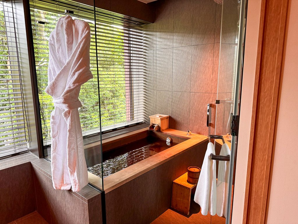  温泉付きの洗面所と風呂場。バスローブが掛かっています。  Onsen bathroom and bath area with a hanging bathrobe. 