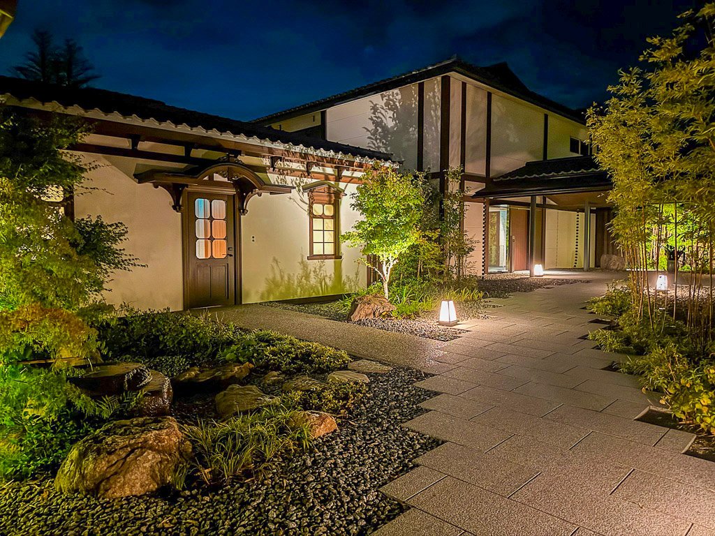  ホテル「紫翠」の宿泊棟、夜の静けさの中で美しくライトアップされた和風建築のエントランス  Guest wing of the hotel “Shisui,” featuring a beautifully lit traditional Japanese entrance in the quiet of the night 