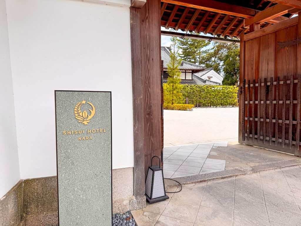  この画像は、奈良にあるSHISUI HOTELの入口を写しています。ホテルの看板と伝統的な日本建築の門が特徴的で、落ち着いた雰囲気が感じられます。  &nbsp;This image shows the entrance of SHISUI HOTEL in Nara. The hotel’s sign and the traditional Japanese architectural gate are the main features, creating a serene atmosphere. 