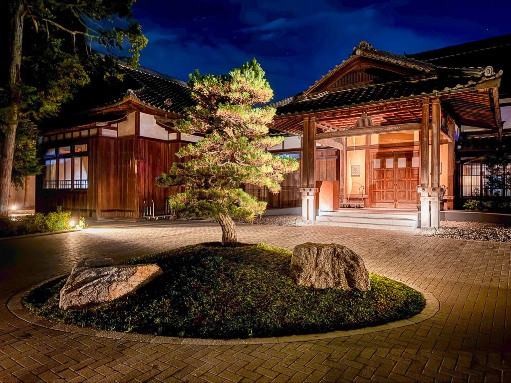  ホテル「紫翠」の夜の外観、和風建築が美しくライトアップされた静かな雰囲気  Night view of the hotel “Shisui,” featuring beautifully lit traditional Japanese architecture in a serene atmosphere 