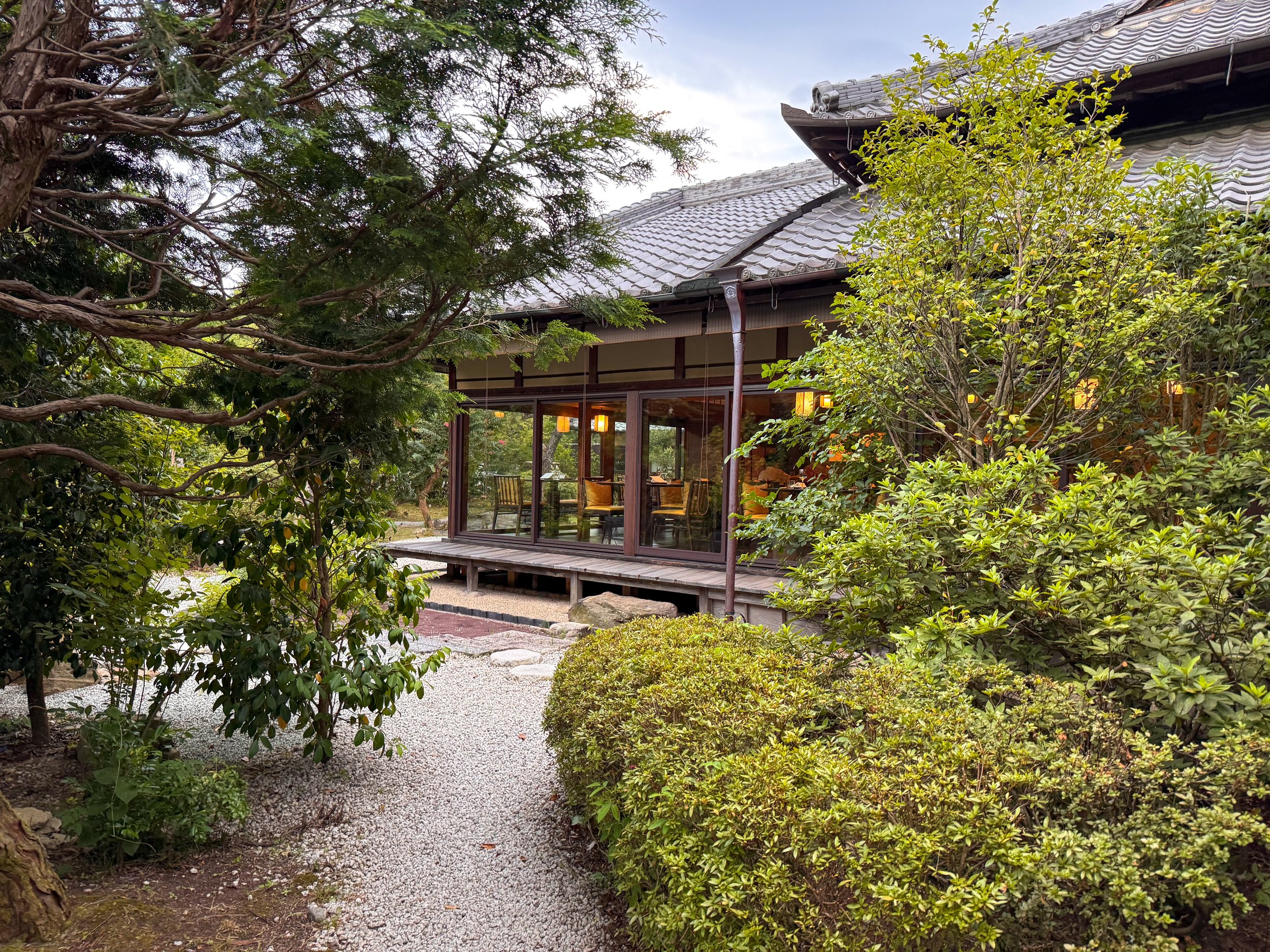  レストラン「翠葉」への朝食への通路、緑豊かな庭園を囲む静かな和風建築  Pathway to breakfast at the restaurant “Suiyo,” surrounded by a lush garden and traditional Japanese architecture 