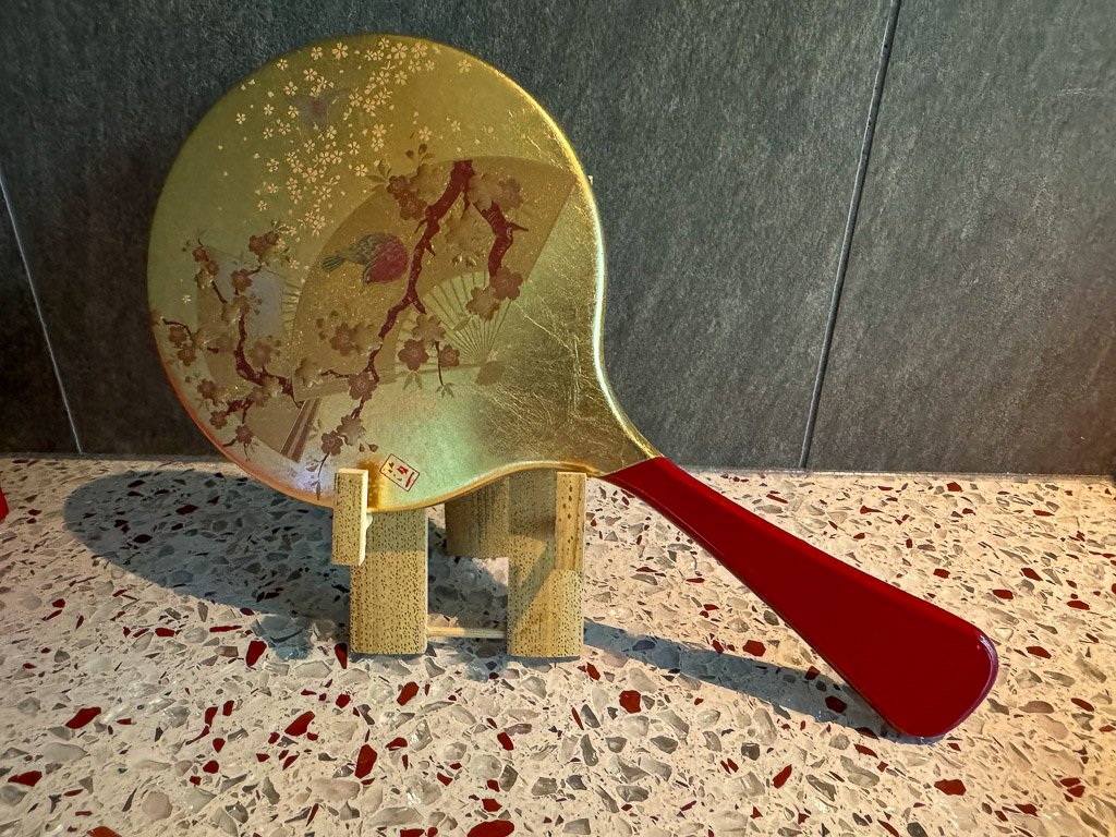  桜と扇を描いた金箔装飾の伝統的な日本の鏡、上品なデザインが特徴  Traditional Japanese mirror with gold leaf, featuring cherry blossoms and fans, showcasing elegant design 