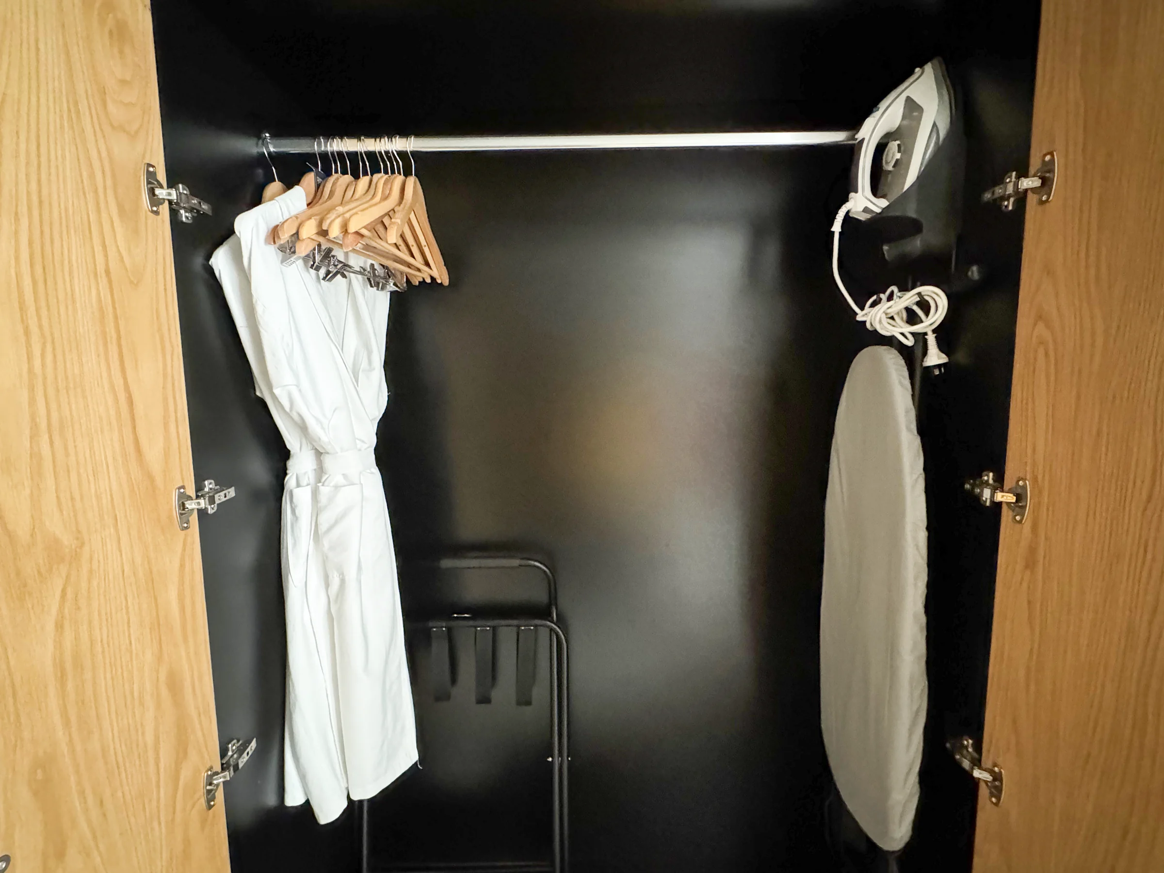 The wardrobe with hangers and an iron.