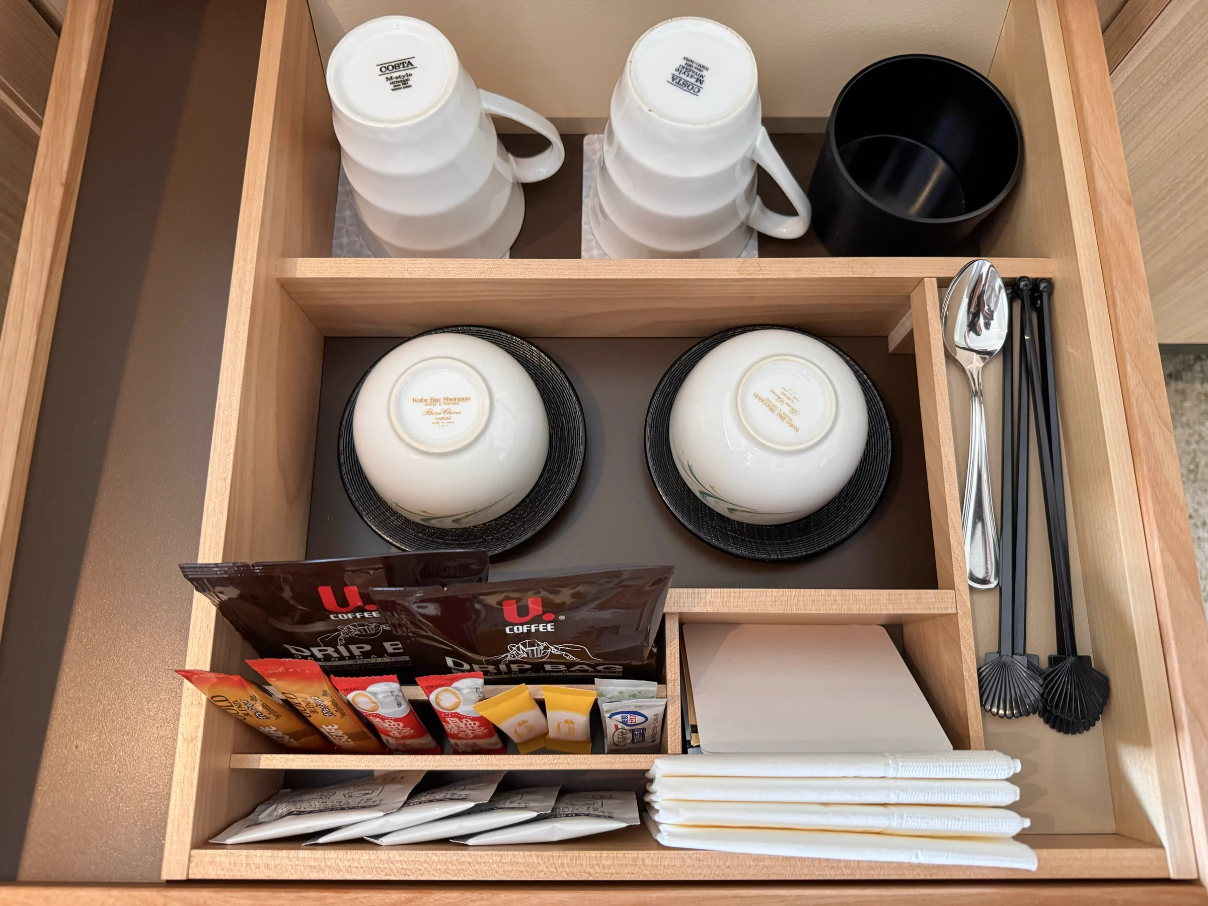 Cups, glasses and a drawer with tea supplies.