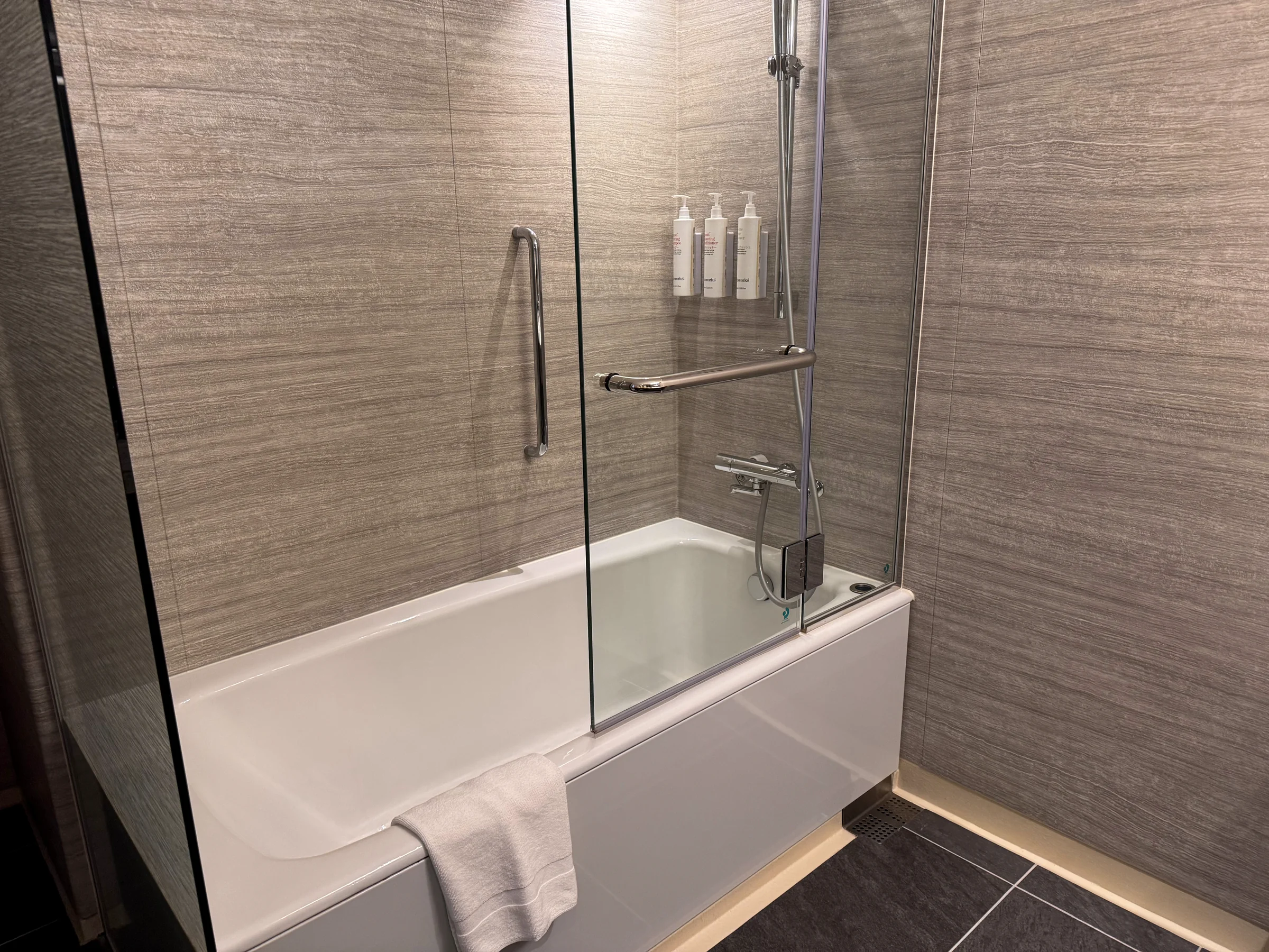 The bathtub and shower with a glass partition