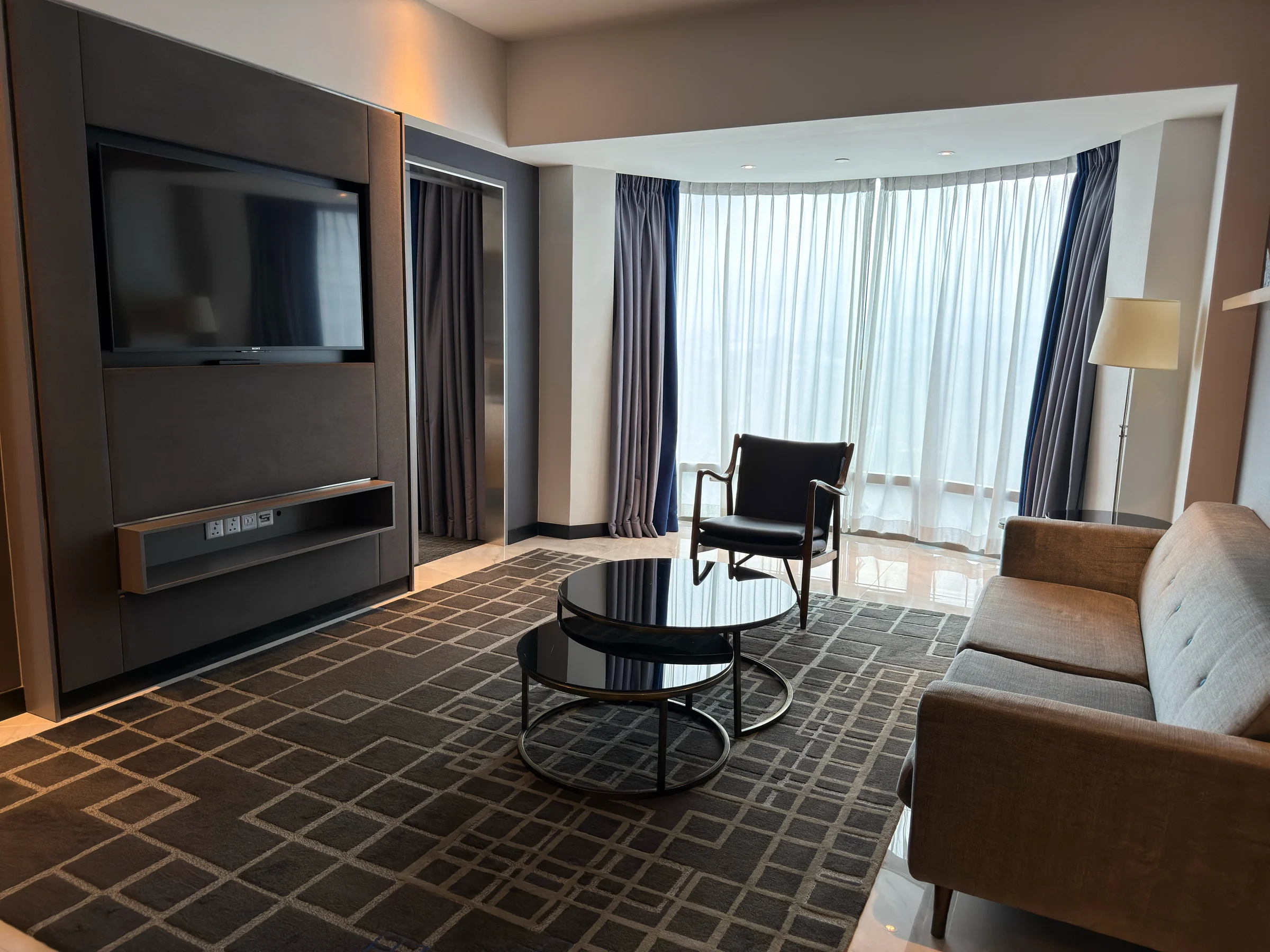 The 27th-floor suite at Le Méridien Kuala Lumpur, with a living room surrounded by large windows