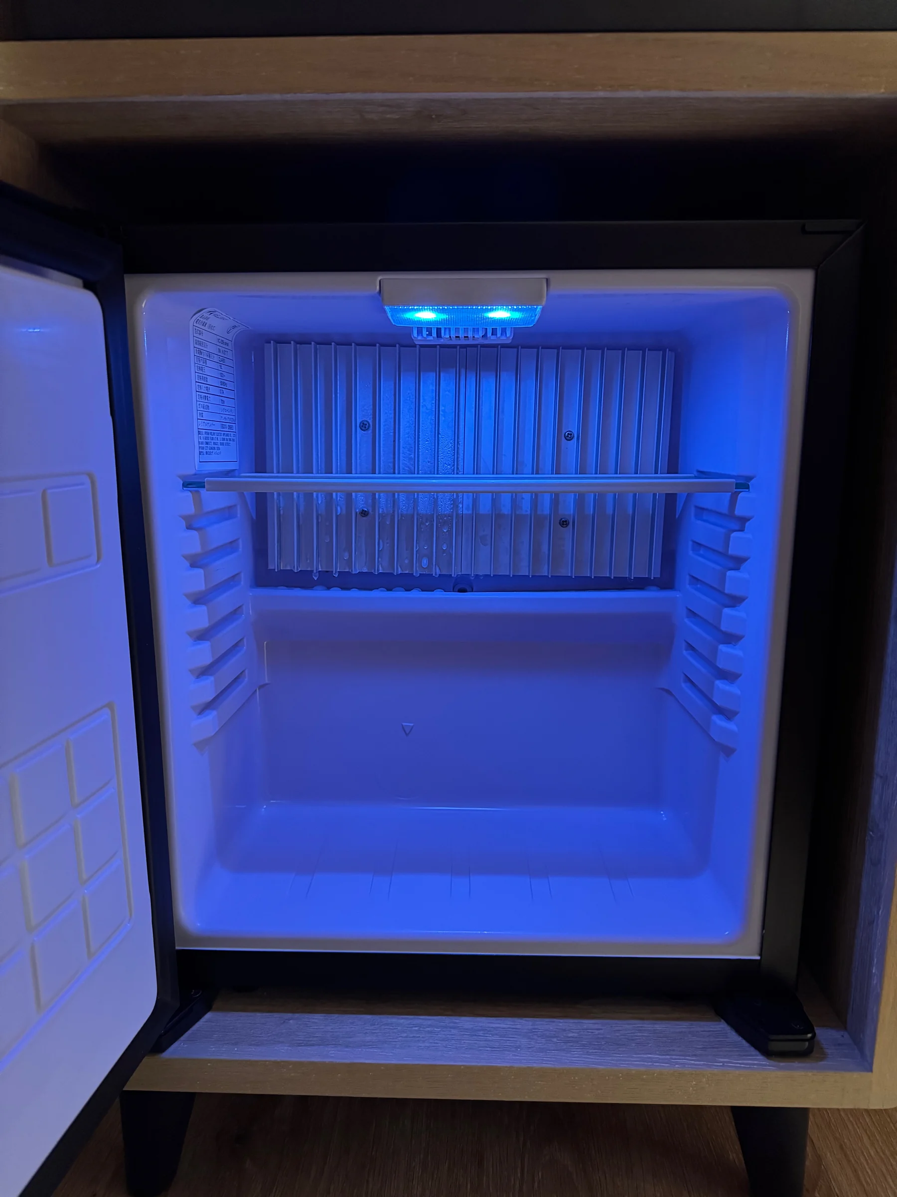 The small empty refrigerator with blue lighting