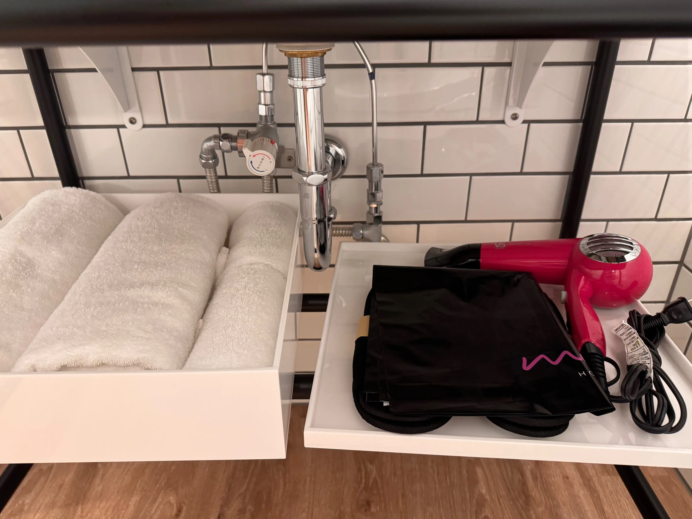 A pink hair dryer and bath towels