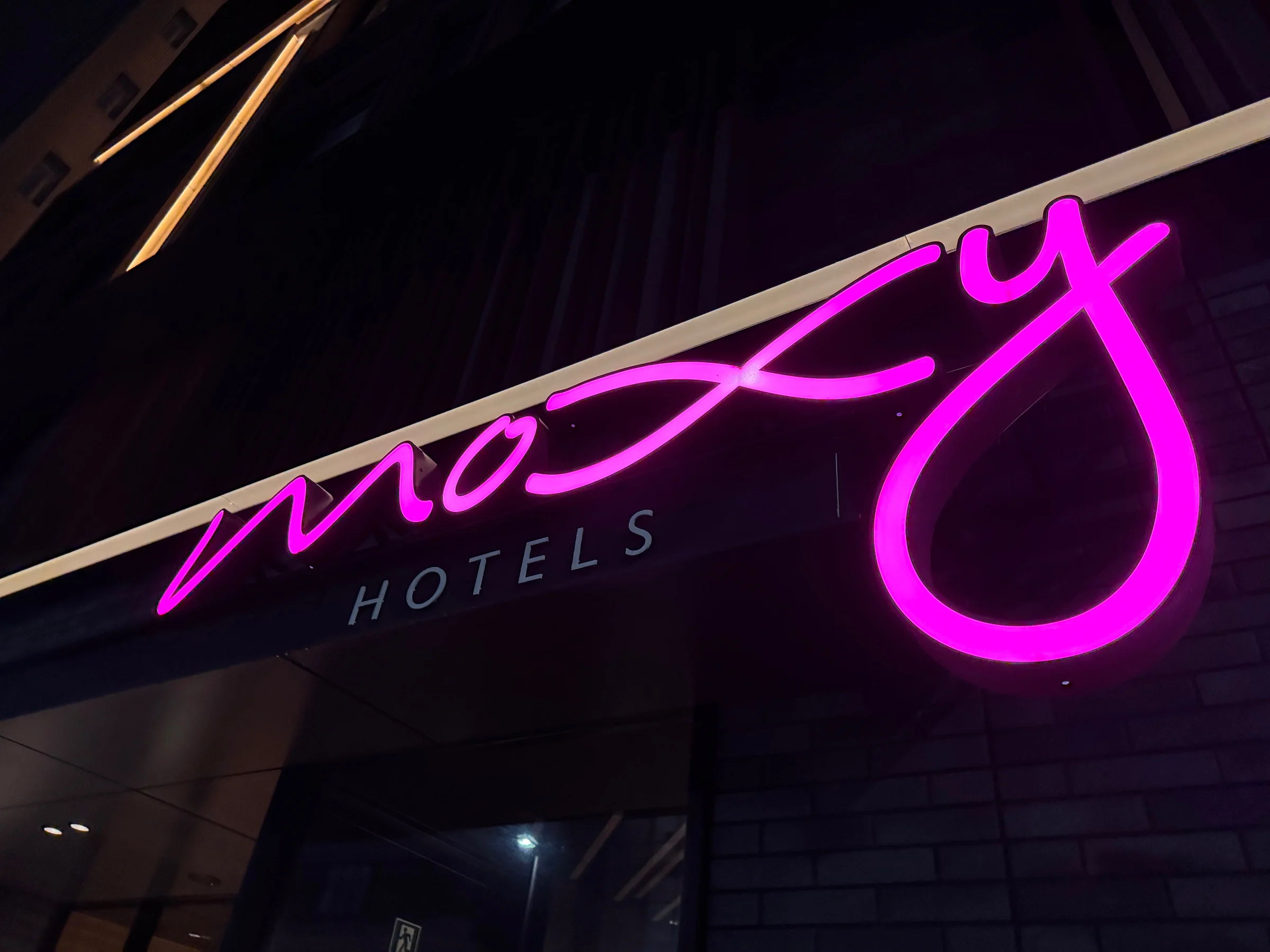 The pink Moxy logo glowing at night