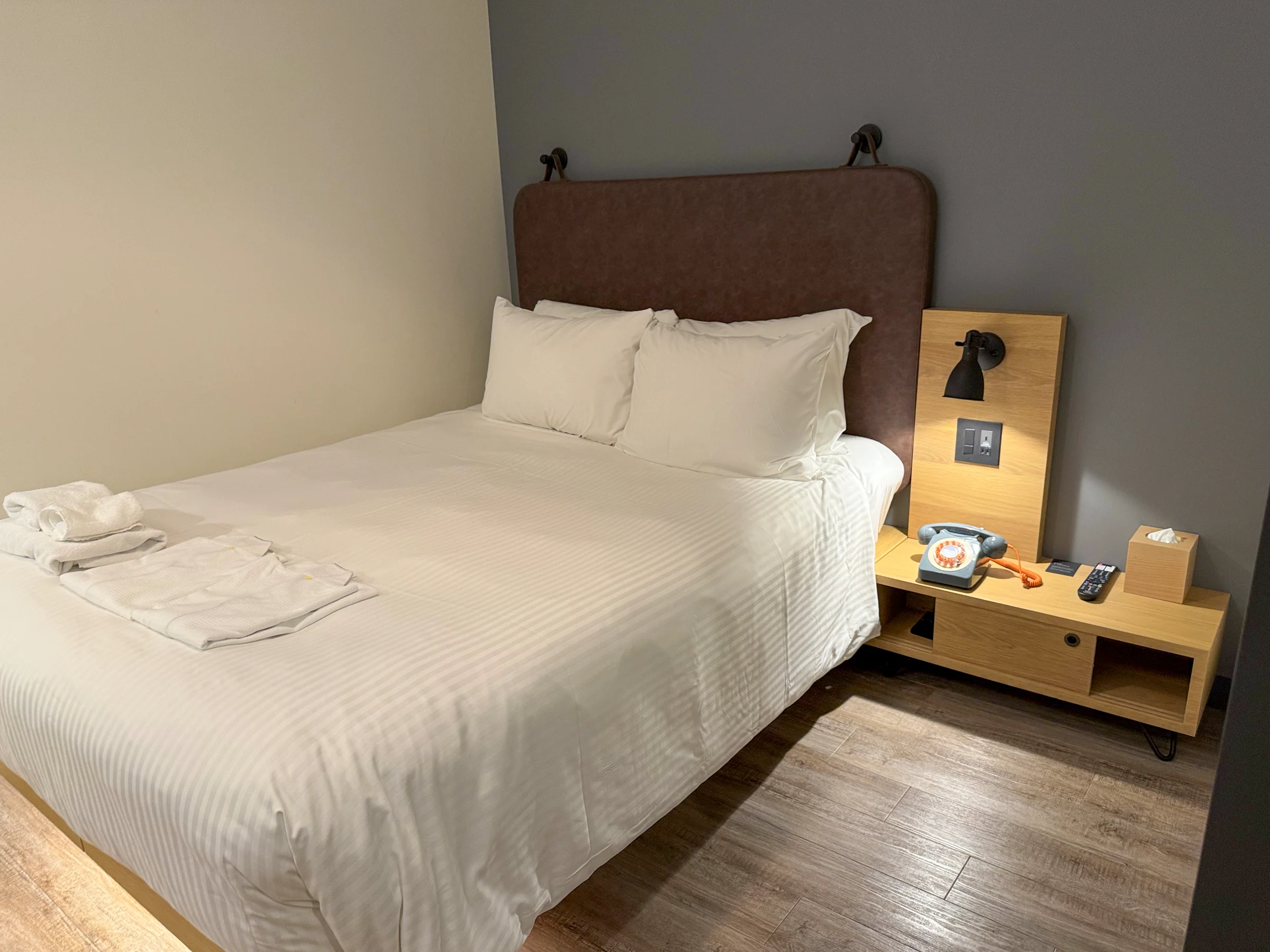 A queen bed and retro telephone.