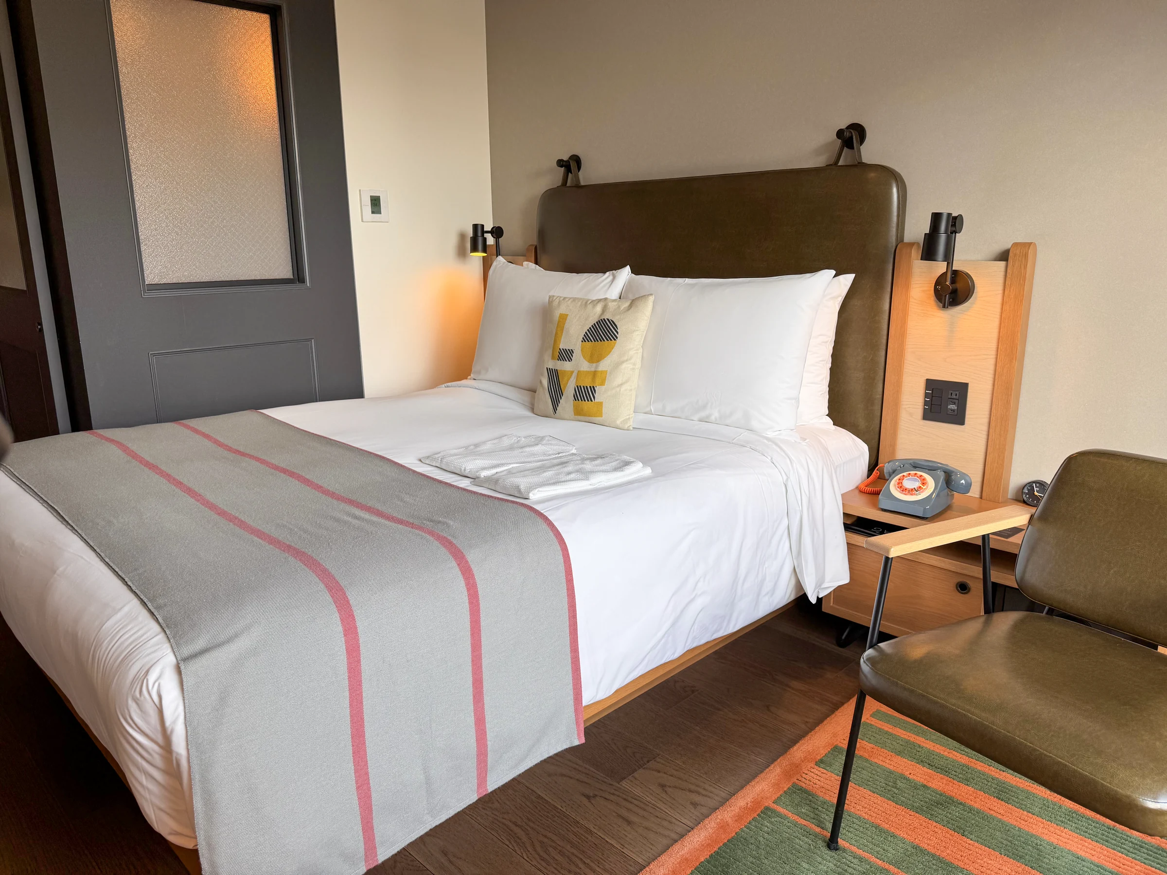 The queen bed, LOVE cushion and window-side chair at Moxy Osaka Shin Umeda