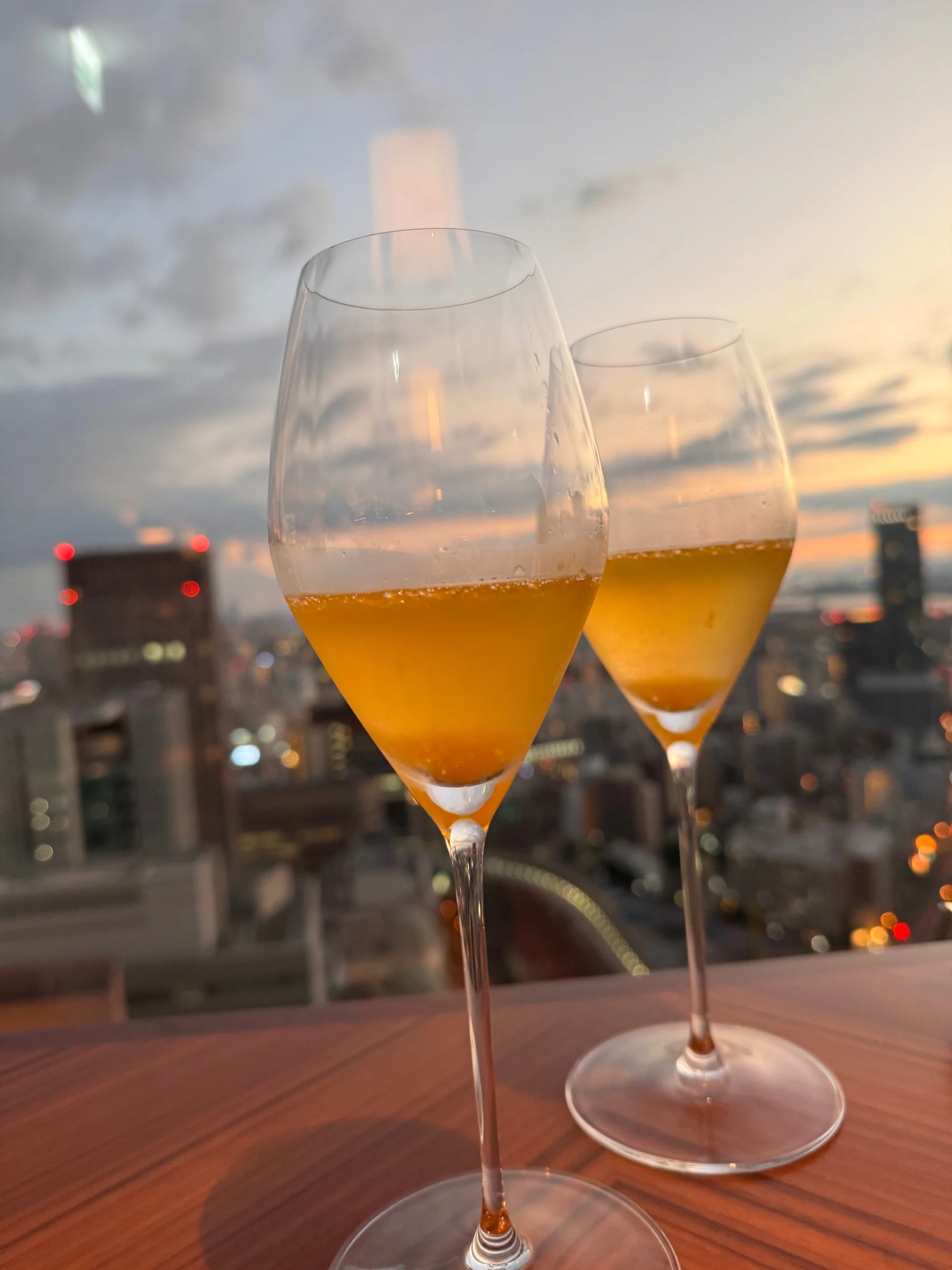 A sparkling wine toast against the city at sunset