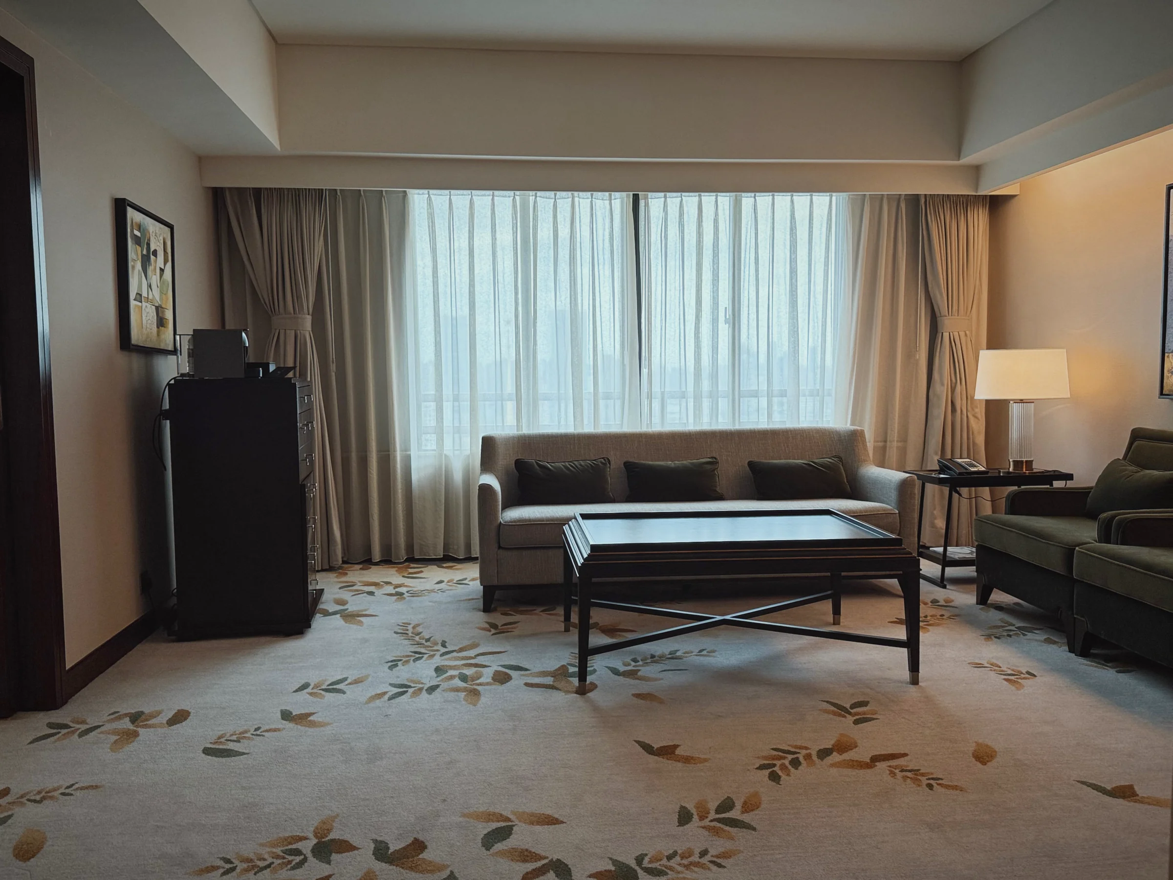 The One-Bedroom Suite at the Portman Shanghai, with a window-side sofa and living room table
