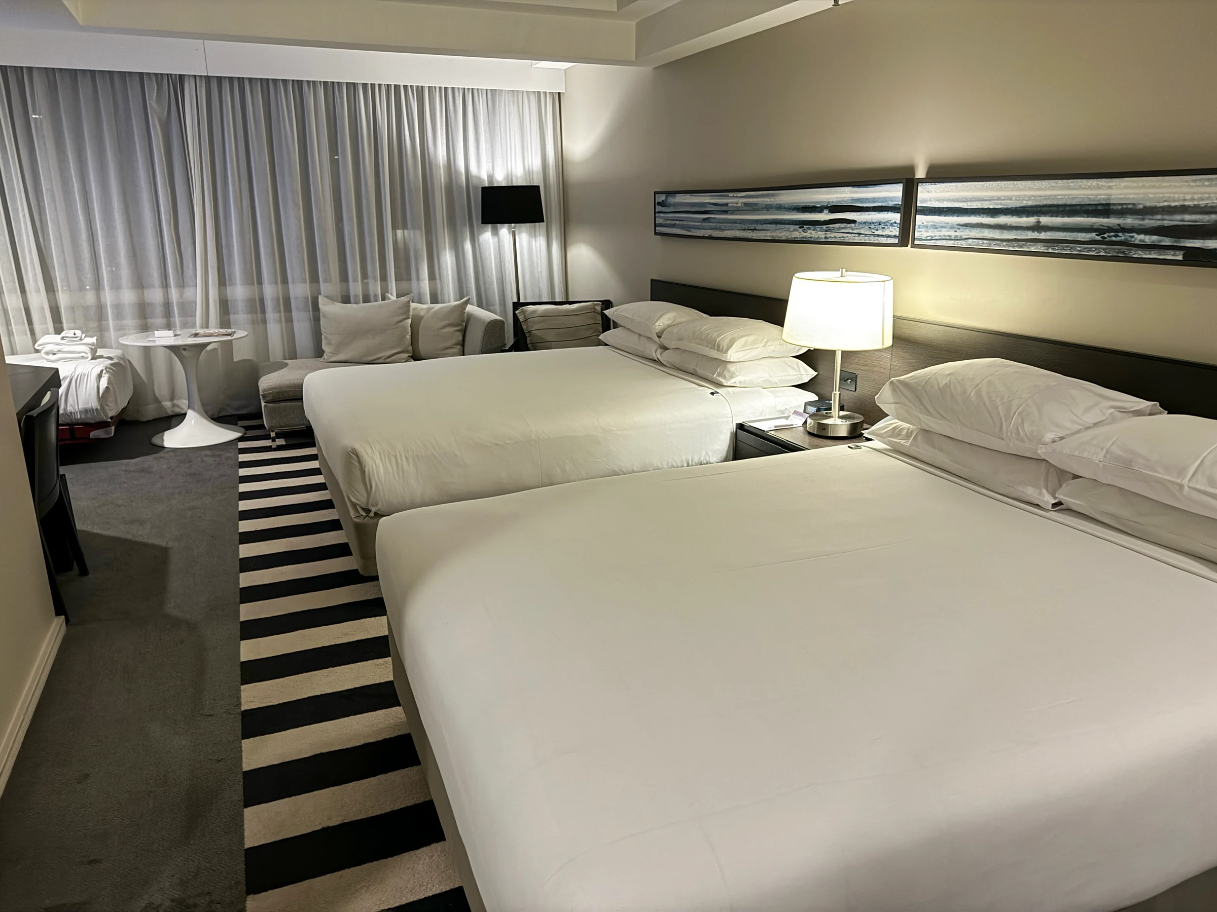 The room at night, with two queen beds and a sofa by the window.