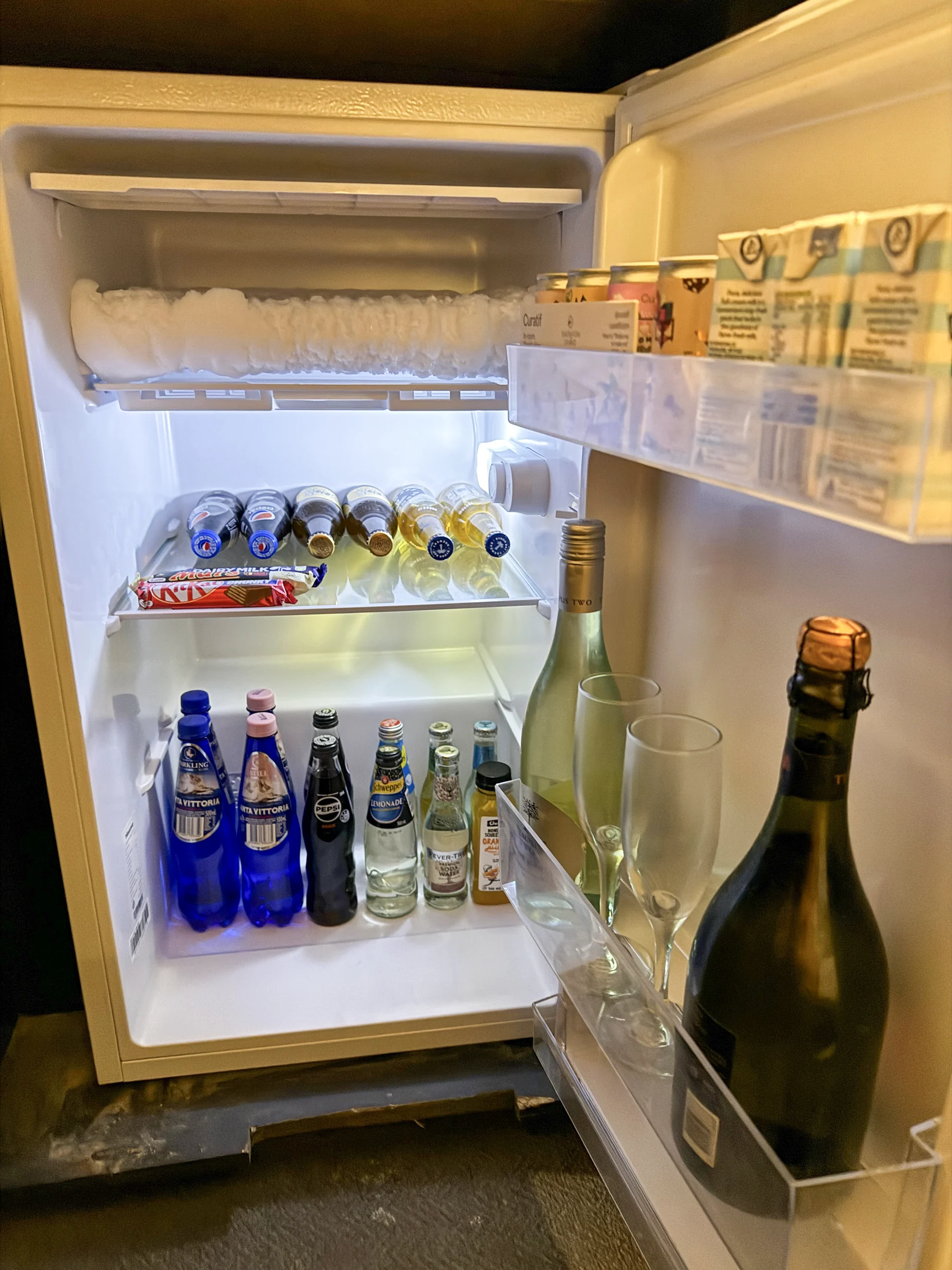 The refrigerator and minibar with glasses.