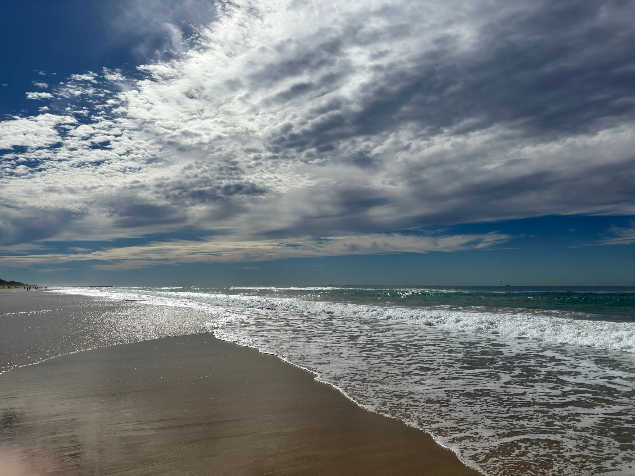 Waves on the sand and clouds overhead.