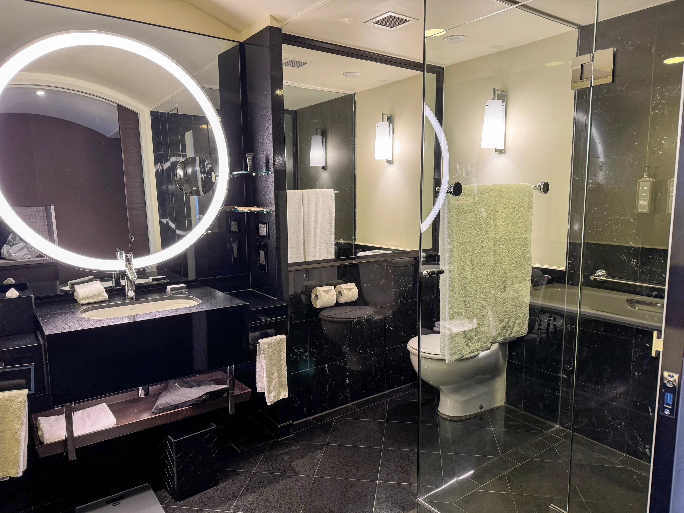 A round illuminated mirror and black-toned vanity.