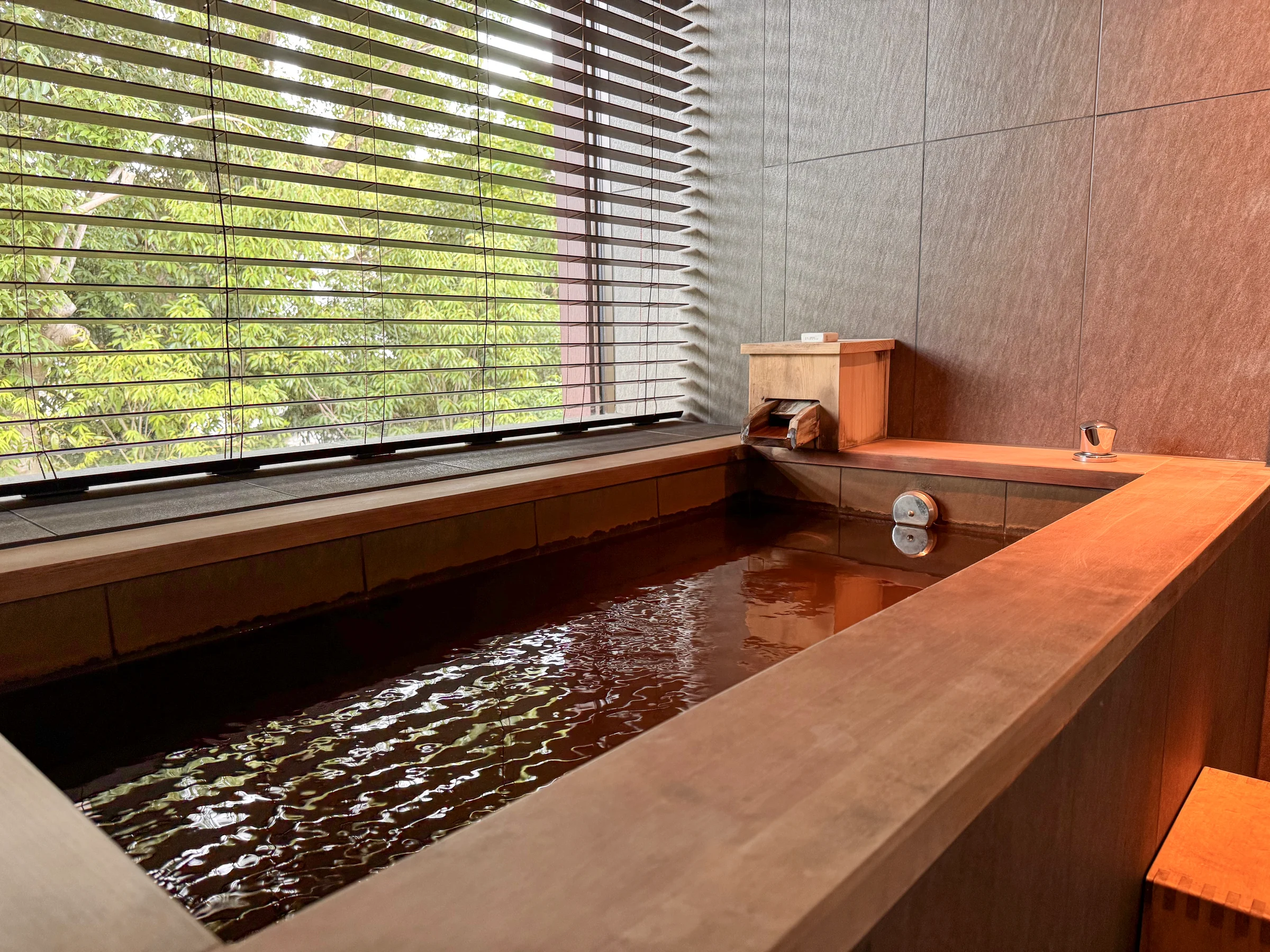 The wooden tub and greenery outside the window.