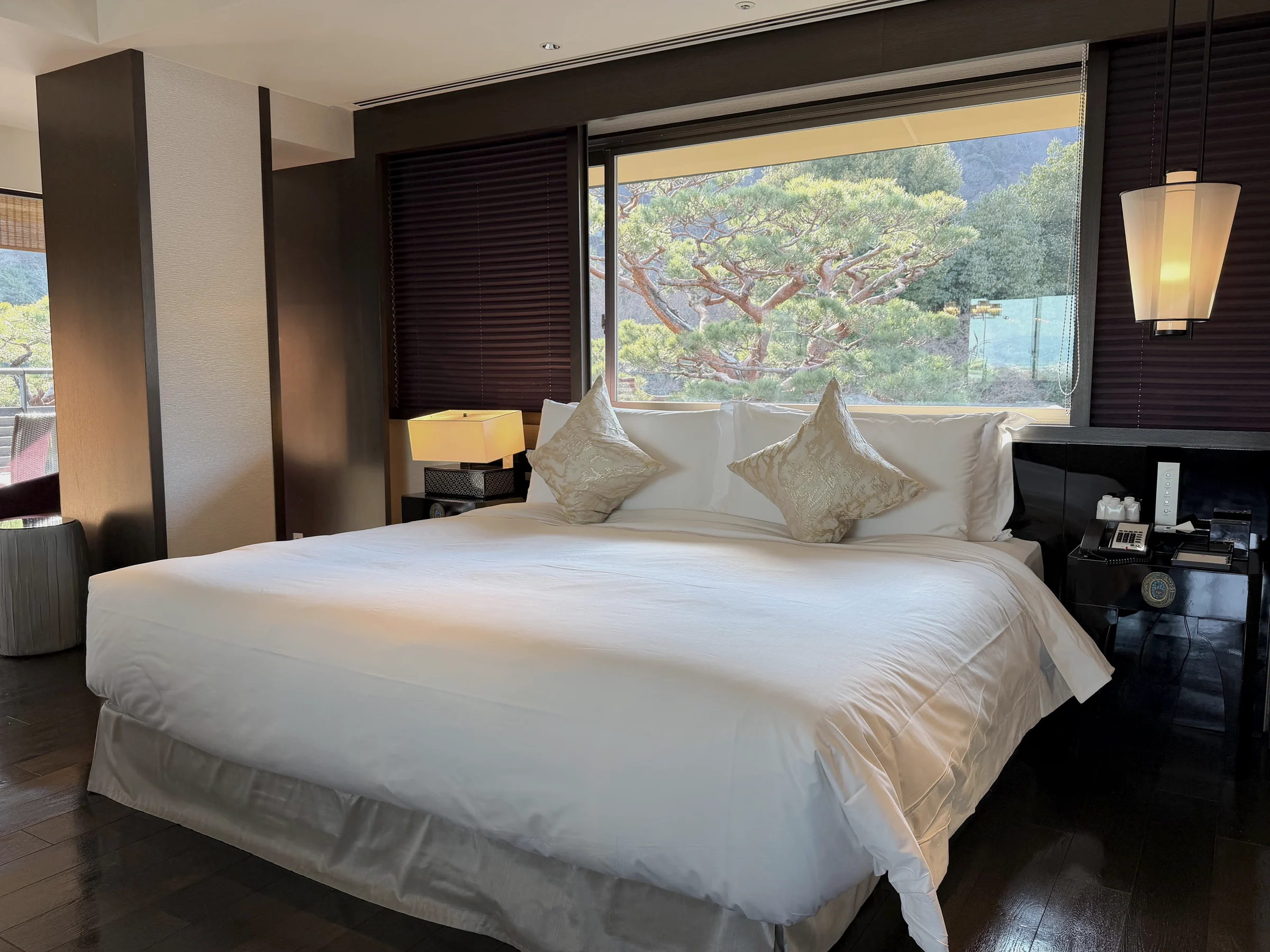 A large bed and trees beyond the windows