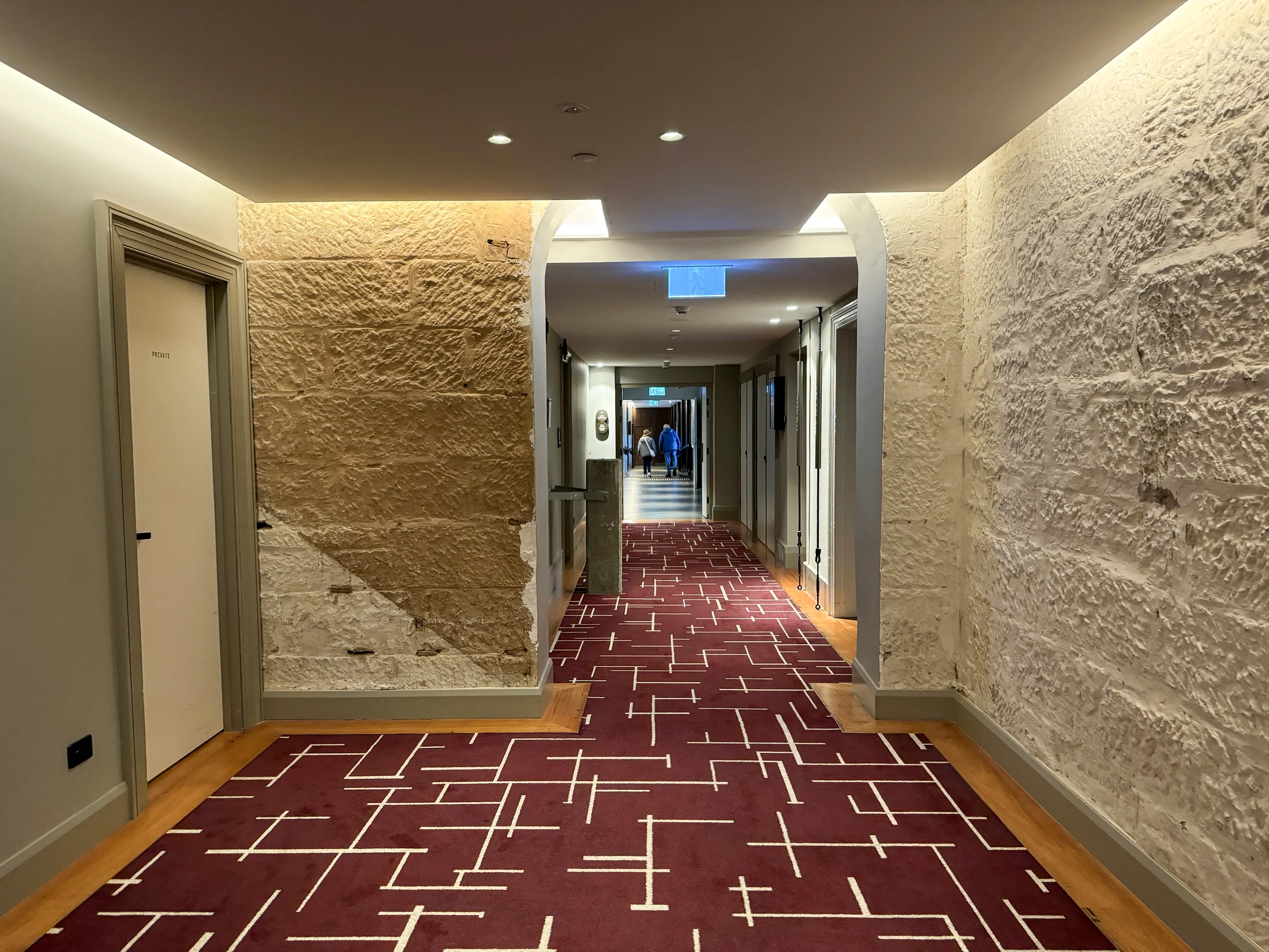 A corridor with stone walls and red carpet.
