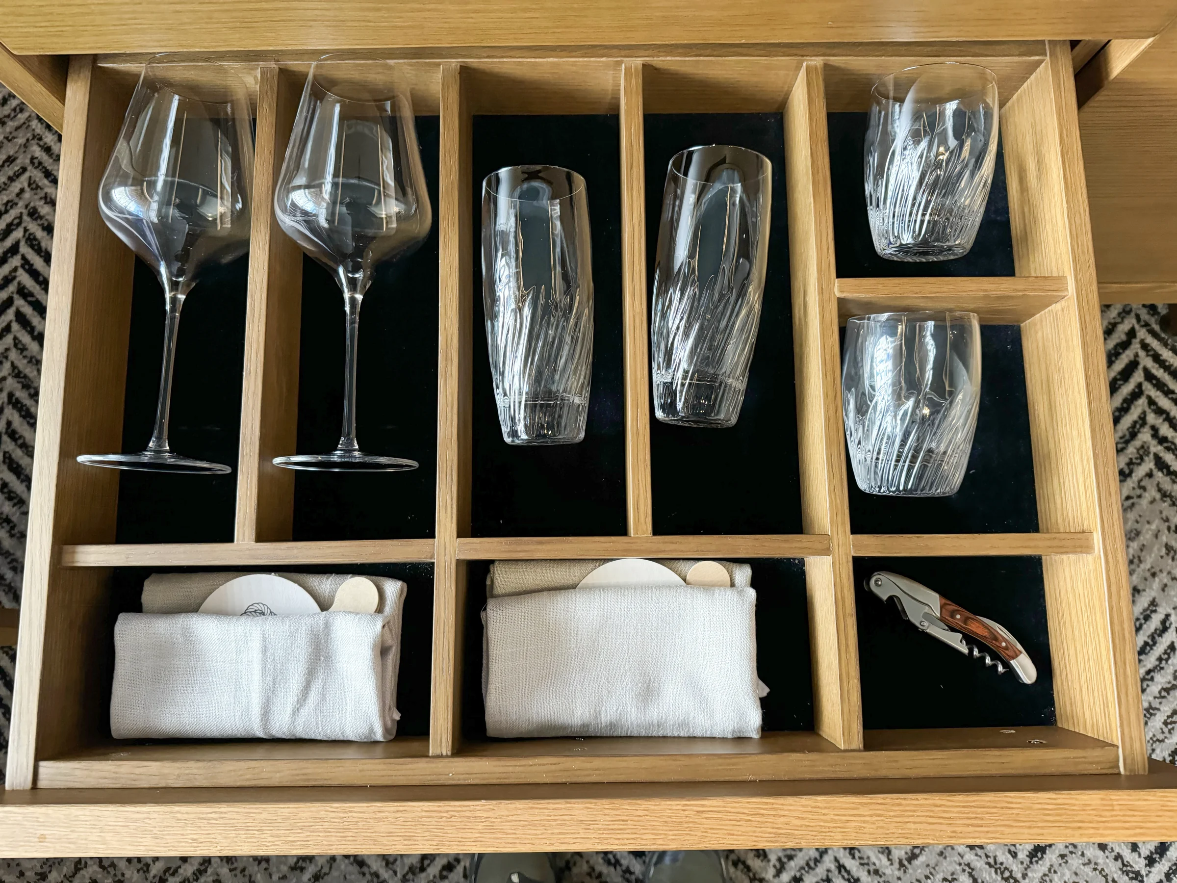 Glasses and cutlery stored in a drawer.
