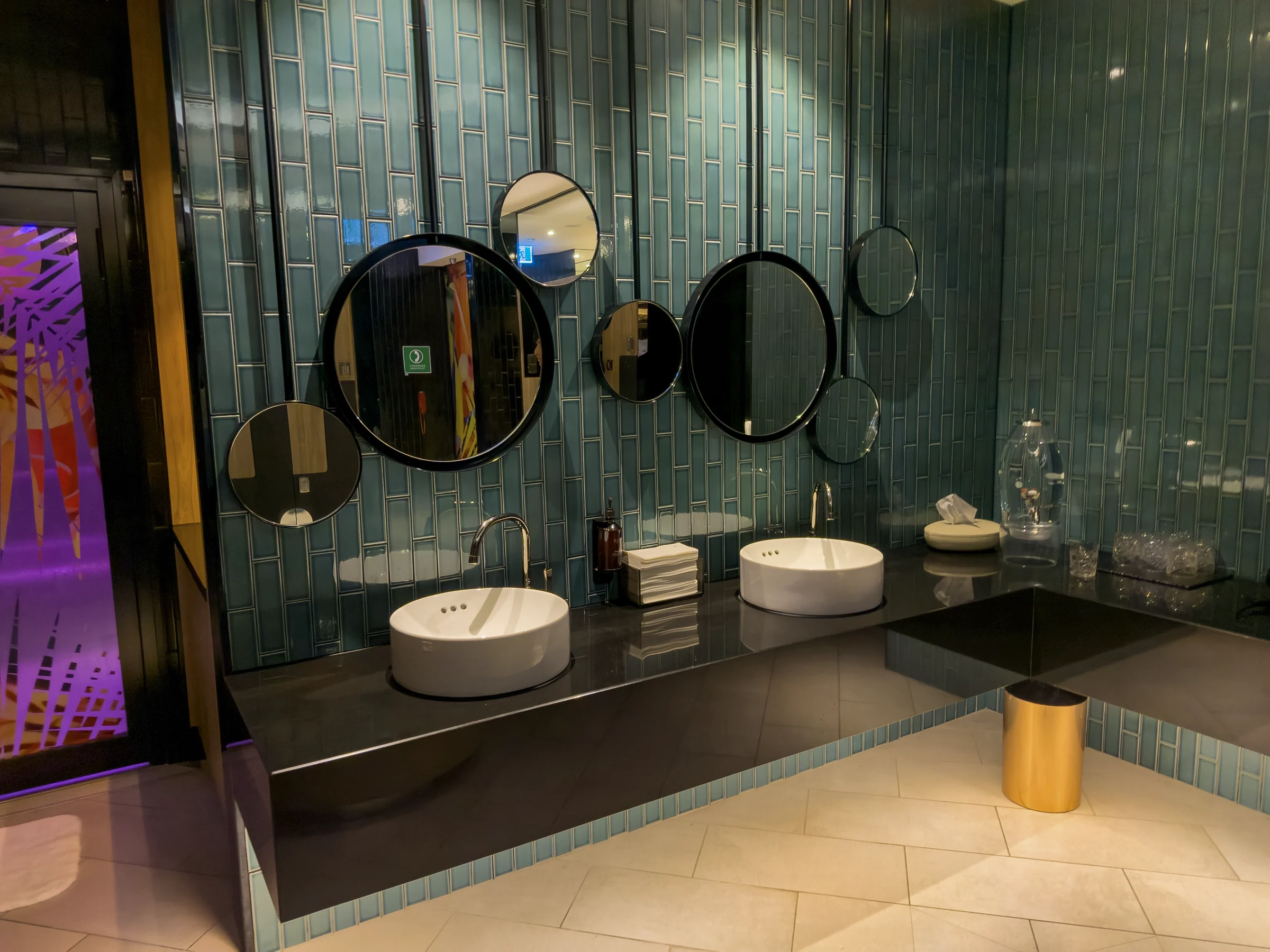Green tiles and a series of round mirrors.