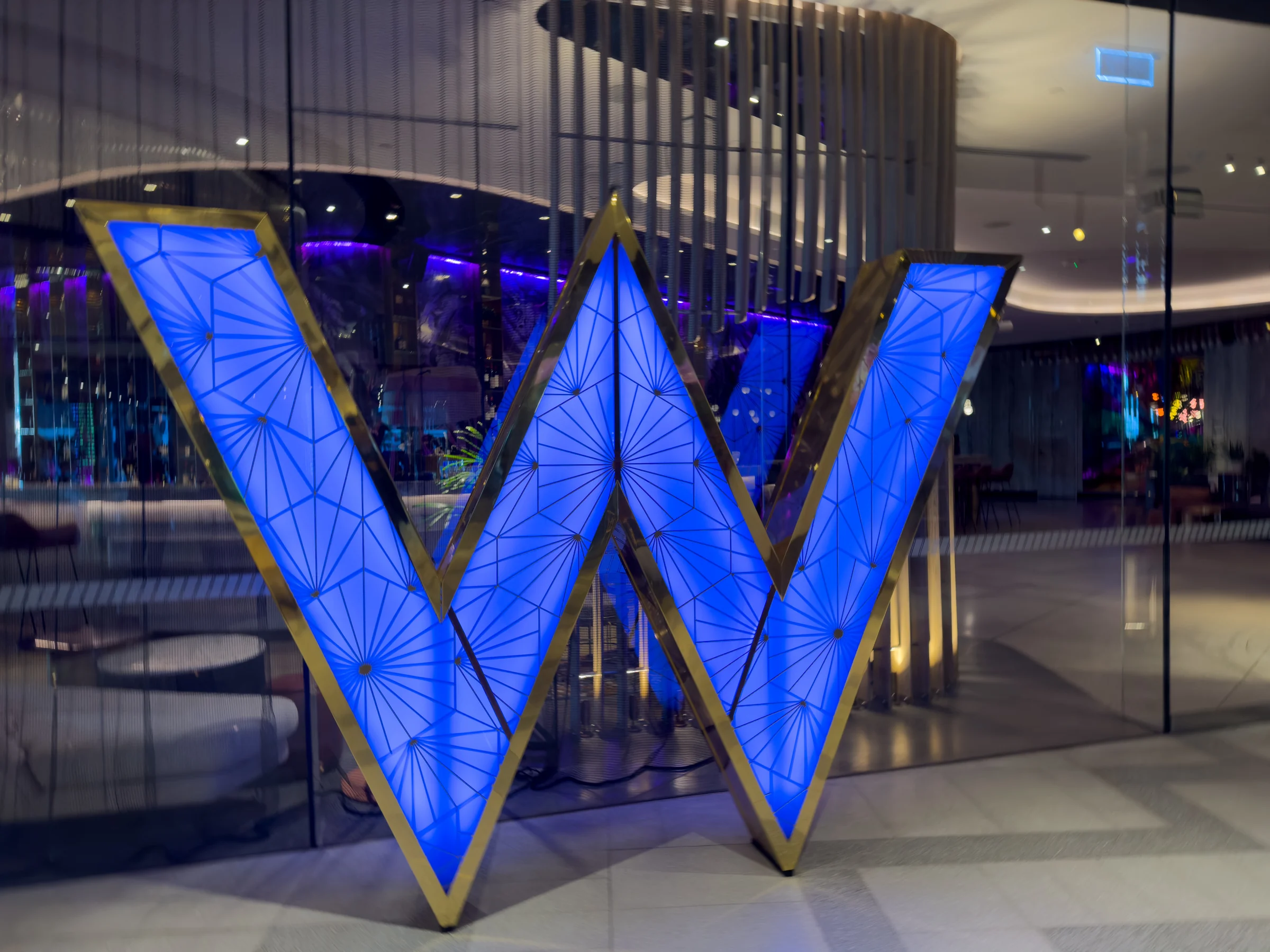 The W glowing blue at the entrance at night.