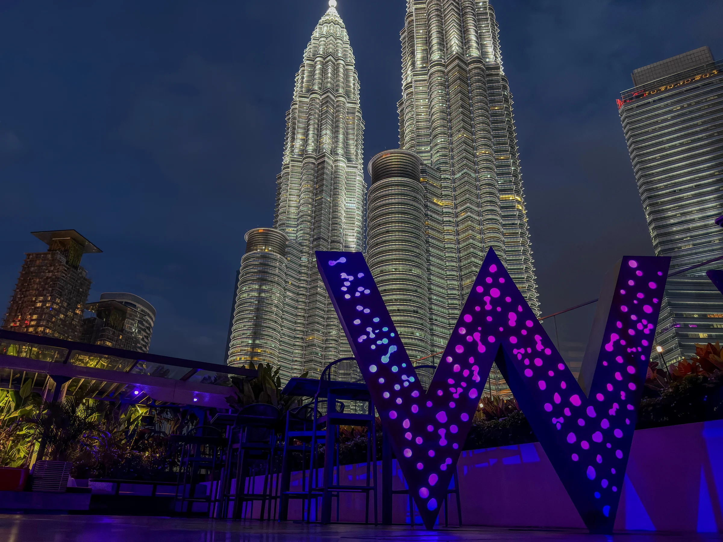 The W glowing purple, and the Twin Towers at night.