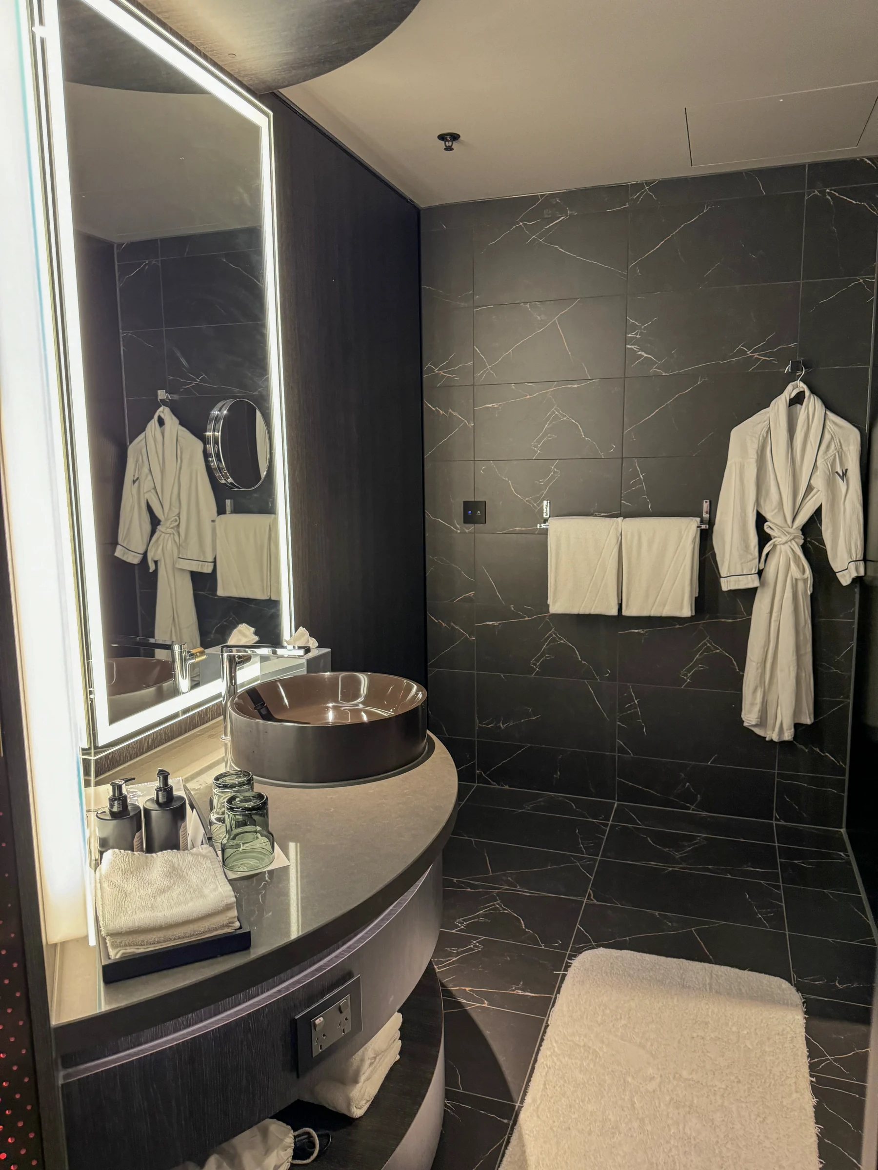 A round washbasin and black stone bathroom.