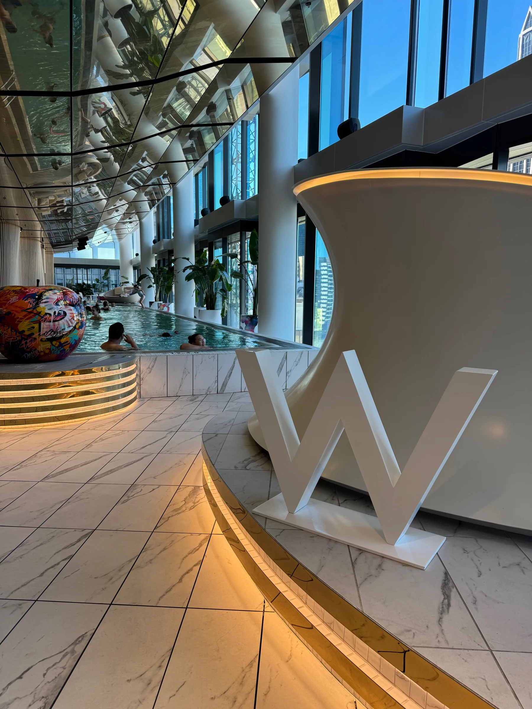 The W sign and the pool beneath a mirrored ceiling.