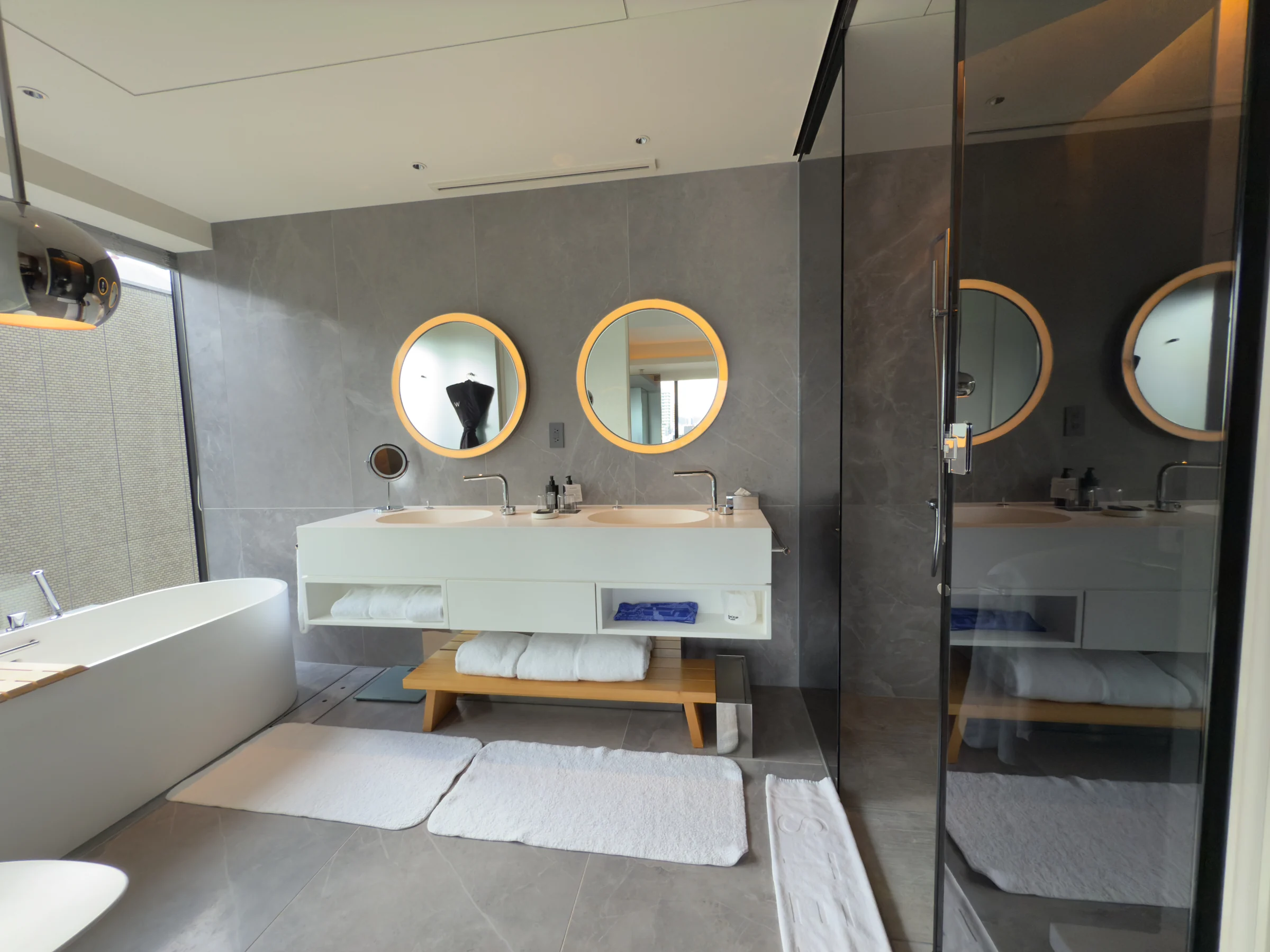 A white bathroom with a round mirror and bathtub