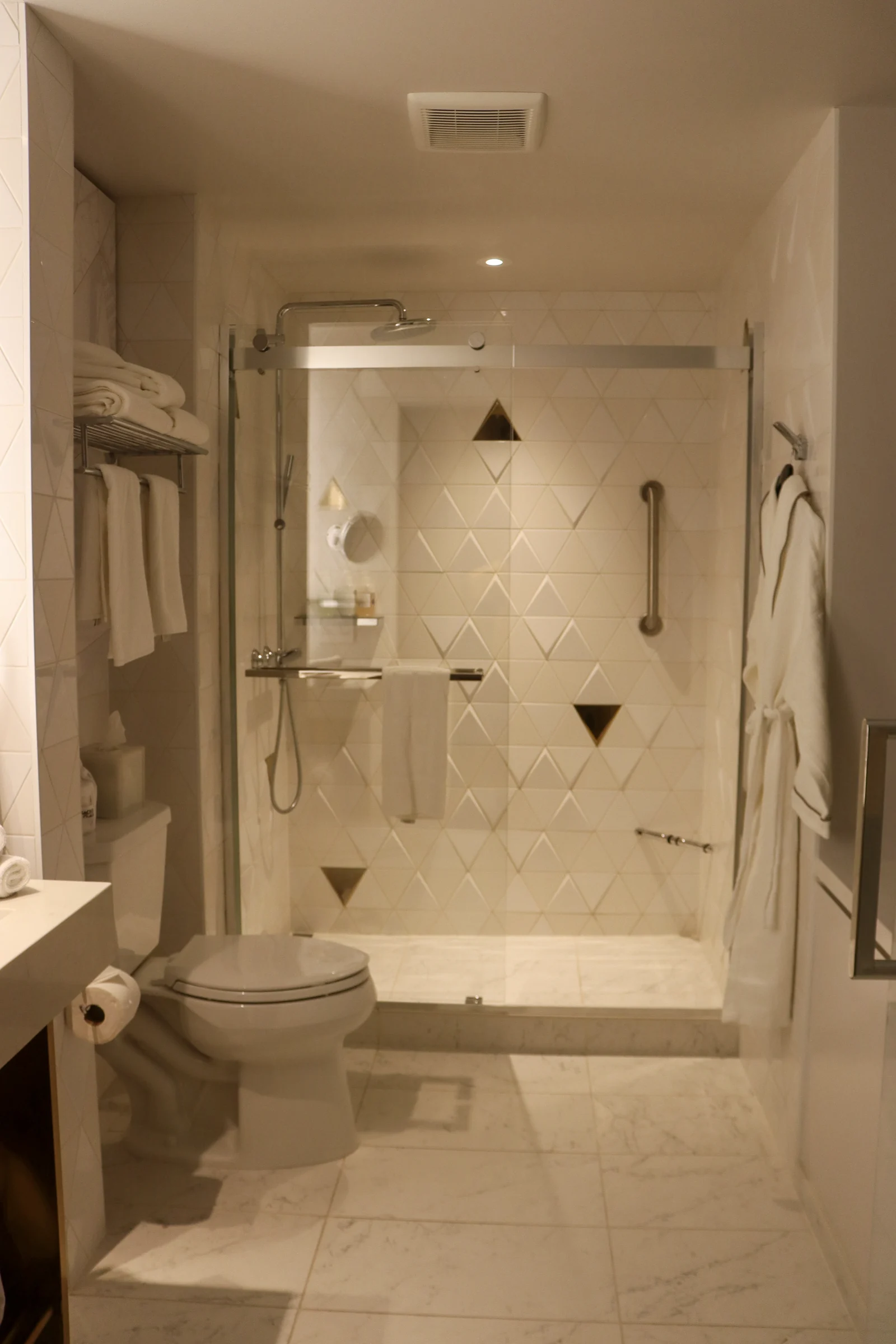 A white tiled shower with triangular patterns.