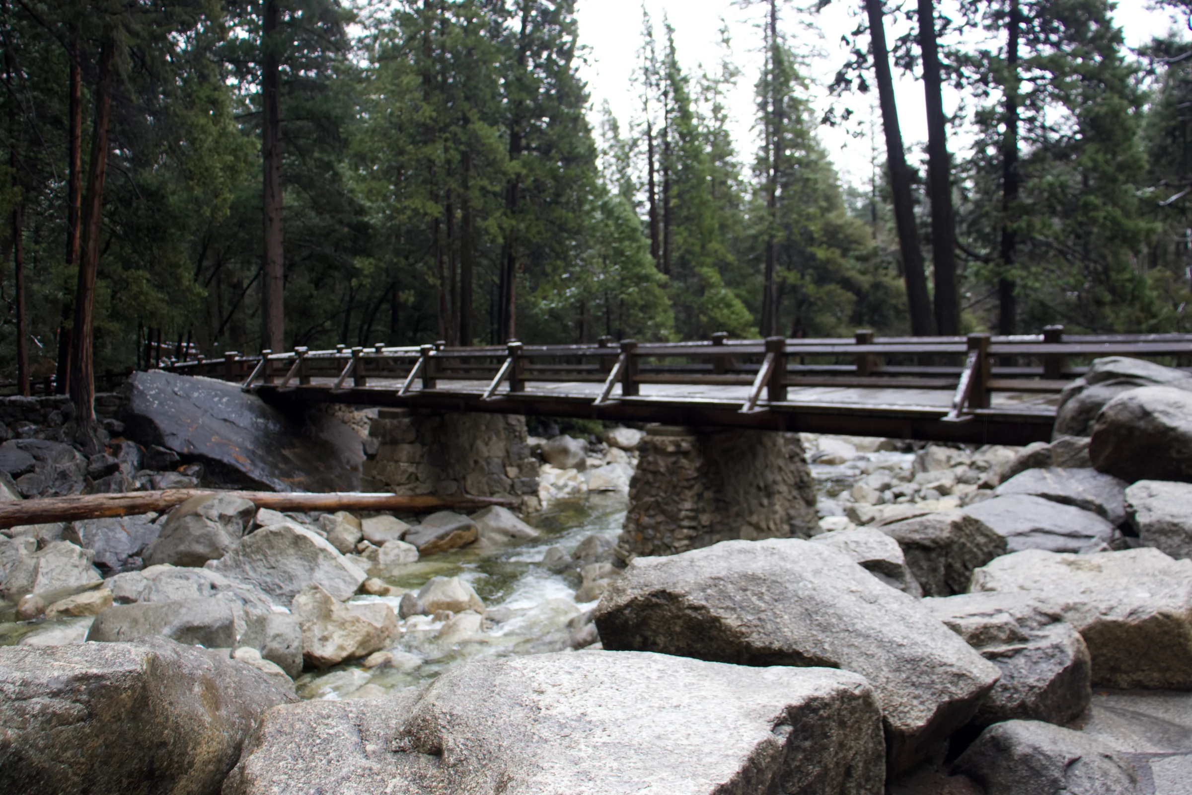 A river flowing between rocks, and a wooden bridge.
