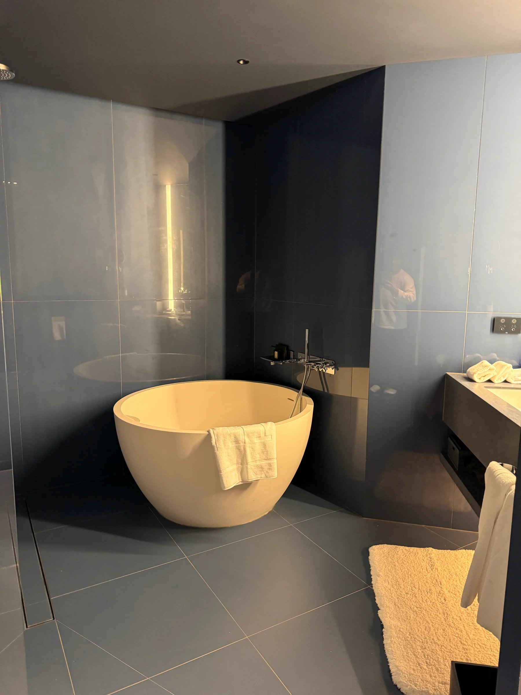A round bathtub surrounded by gray tiles.