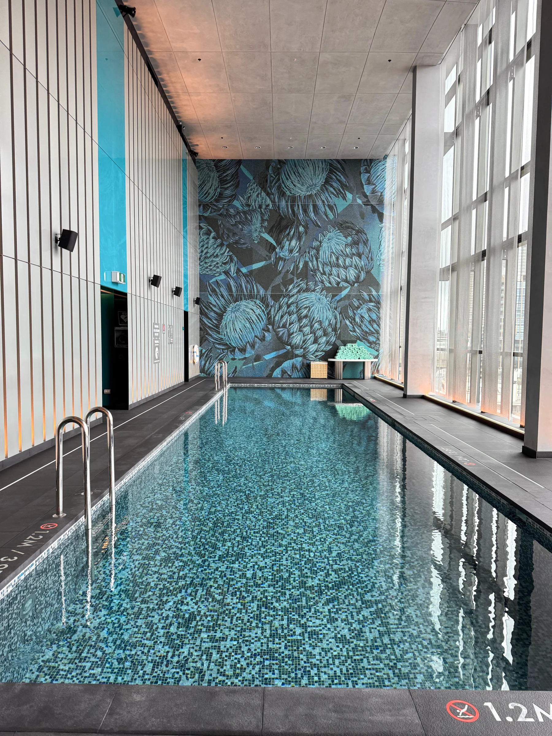 The indoor pool with tall windows and tiles.