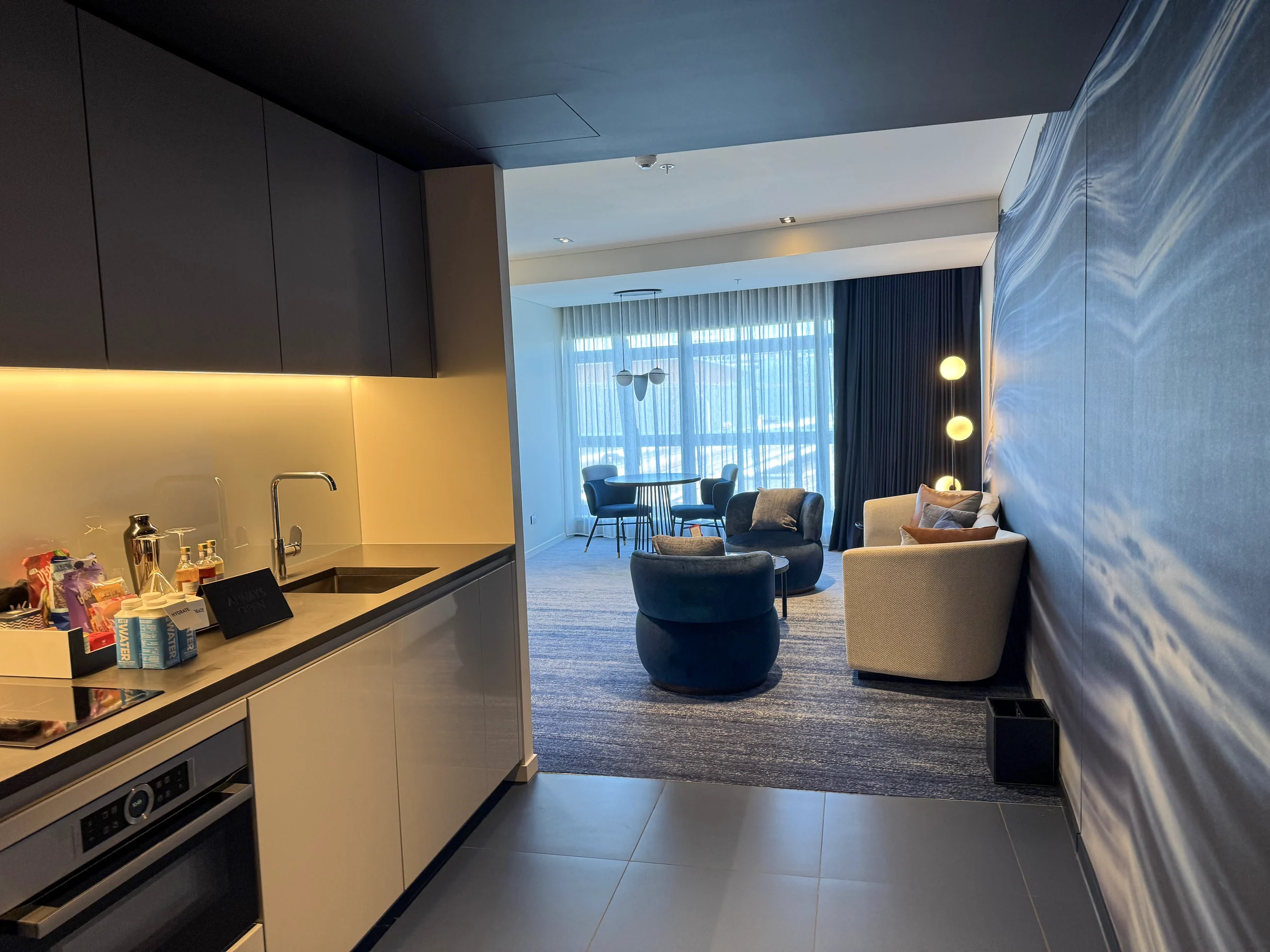 W Sydney's Oasis Studio, with a blue-walled living room beyond the kitchen