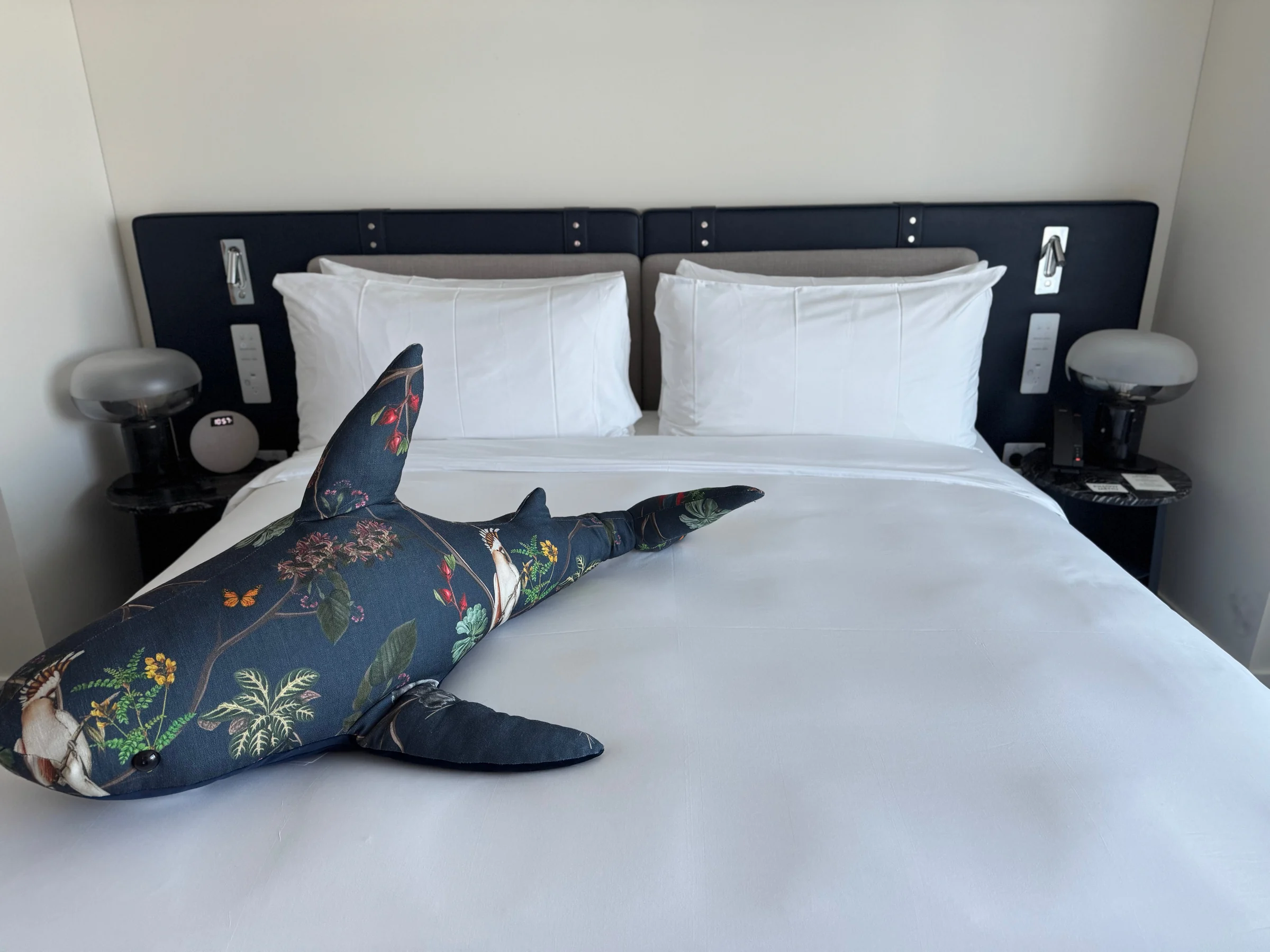 A characteristically W stuffed shark on the bed.
