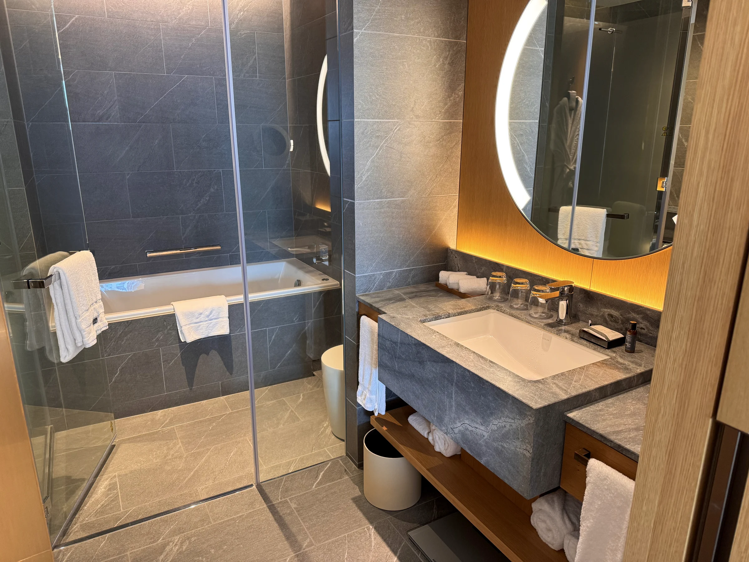 A round mirror and stone vanity counter