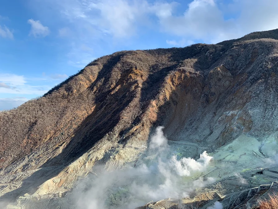 雲と噴気に包まれる山の斜面